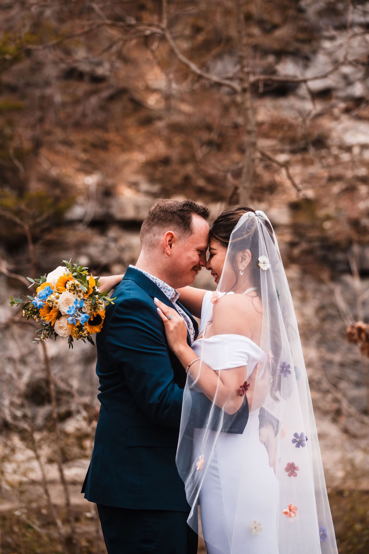 An intimate wedding moment captured against a backdrop of rocky cliffs and fall colors.