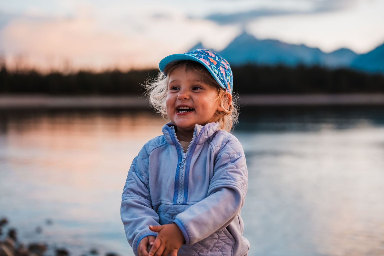 Children enjoying sunset views by mountain lake in matching blue sweatshirts.