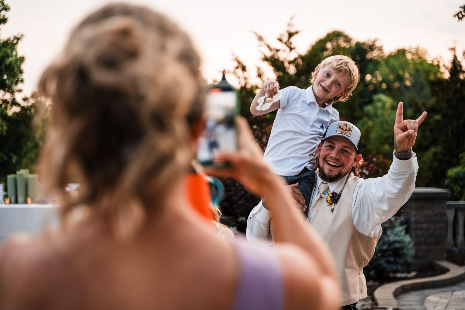 A couple shares a joyful sunset dance moment on a paved outdoor patio surrounded by greenery.