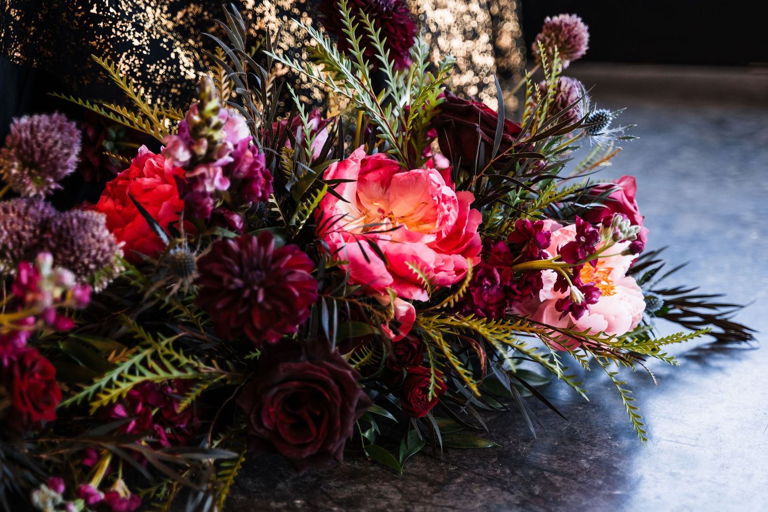 Vibrant wedding floral arrangement featuring deep red roses and purple blooms.