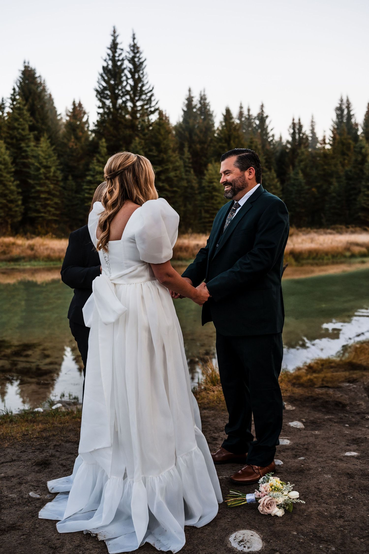 A wedding ceremony by a serene lake surrounded by evergreen trees.