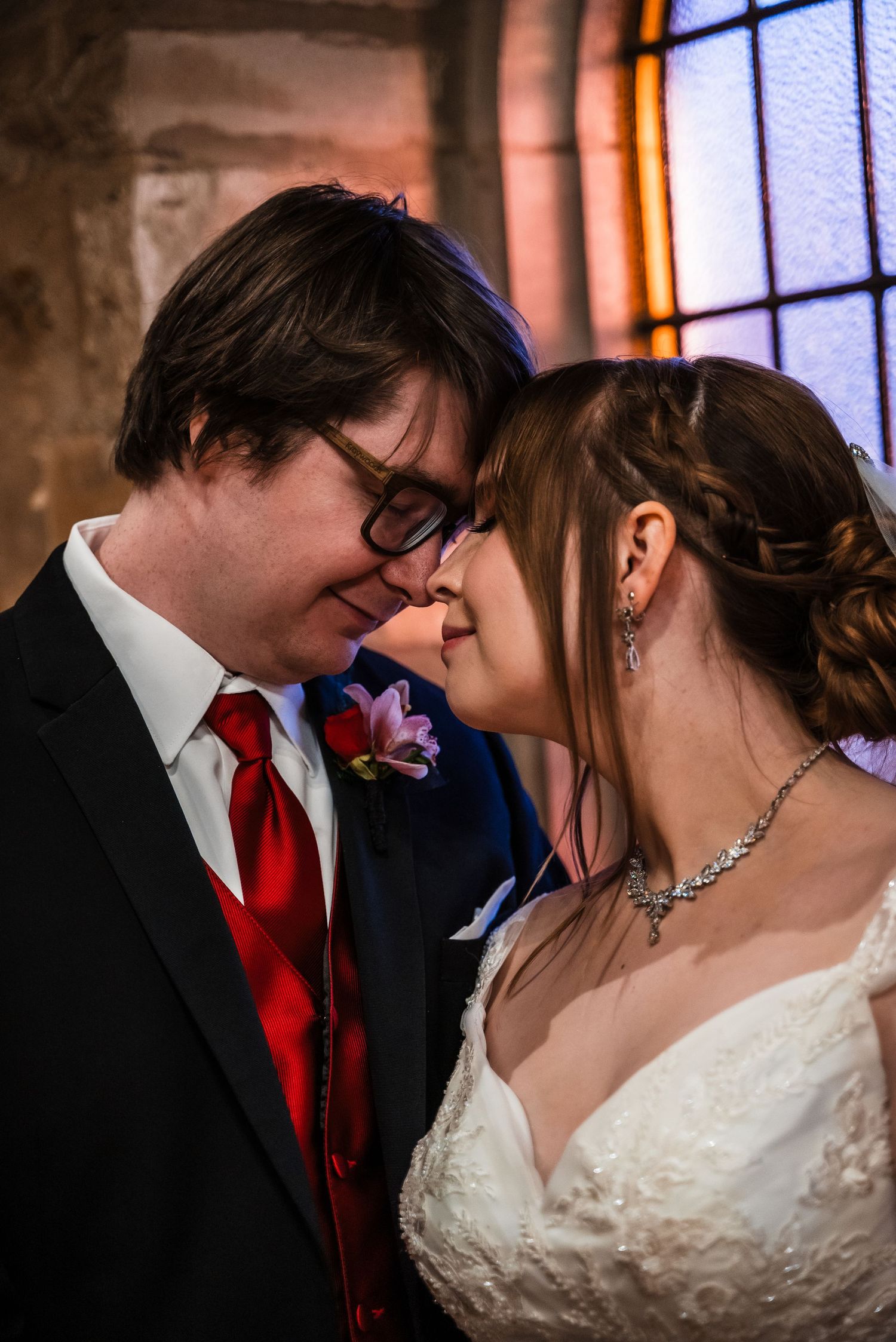 Intimate moment between newlyweds sharing a tender moment in chapel lighting.