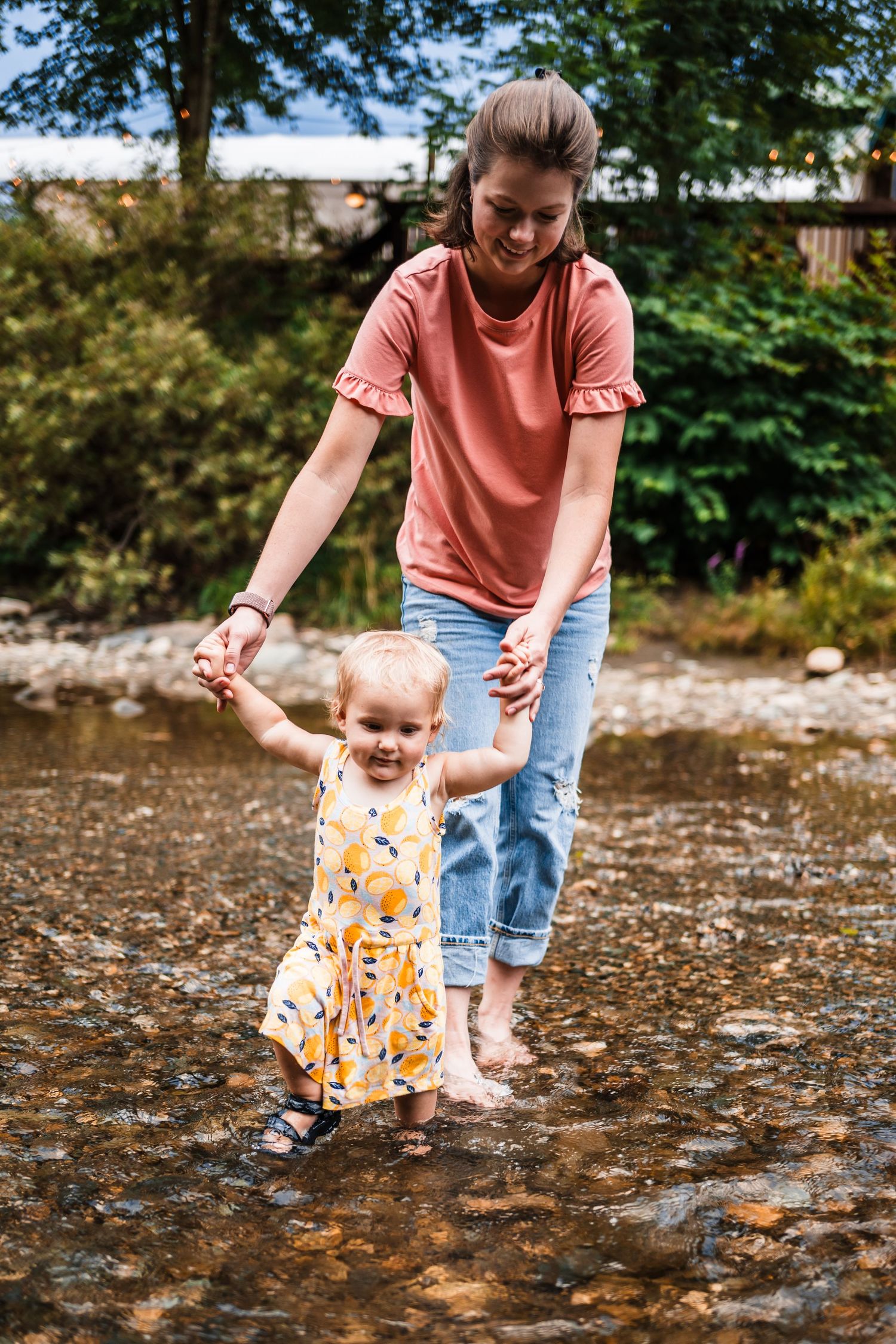 Parent and child playing in a shallow creek on a sunny summer day.
