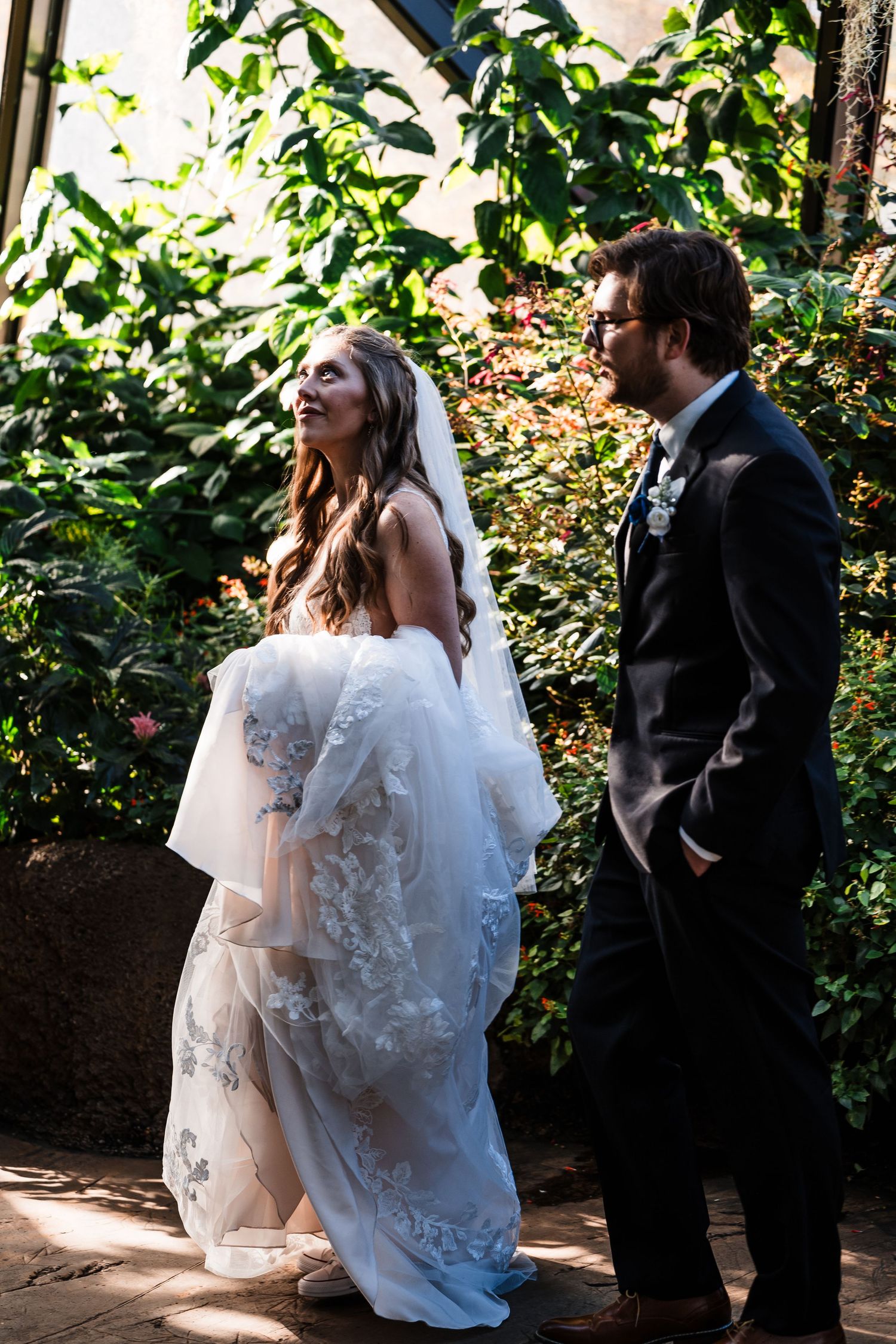 Wedding couple shares a sunlit moment in a lush garden setting.