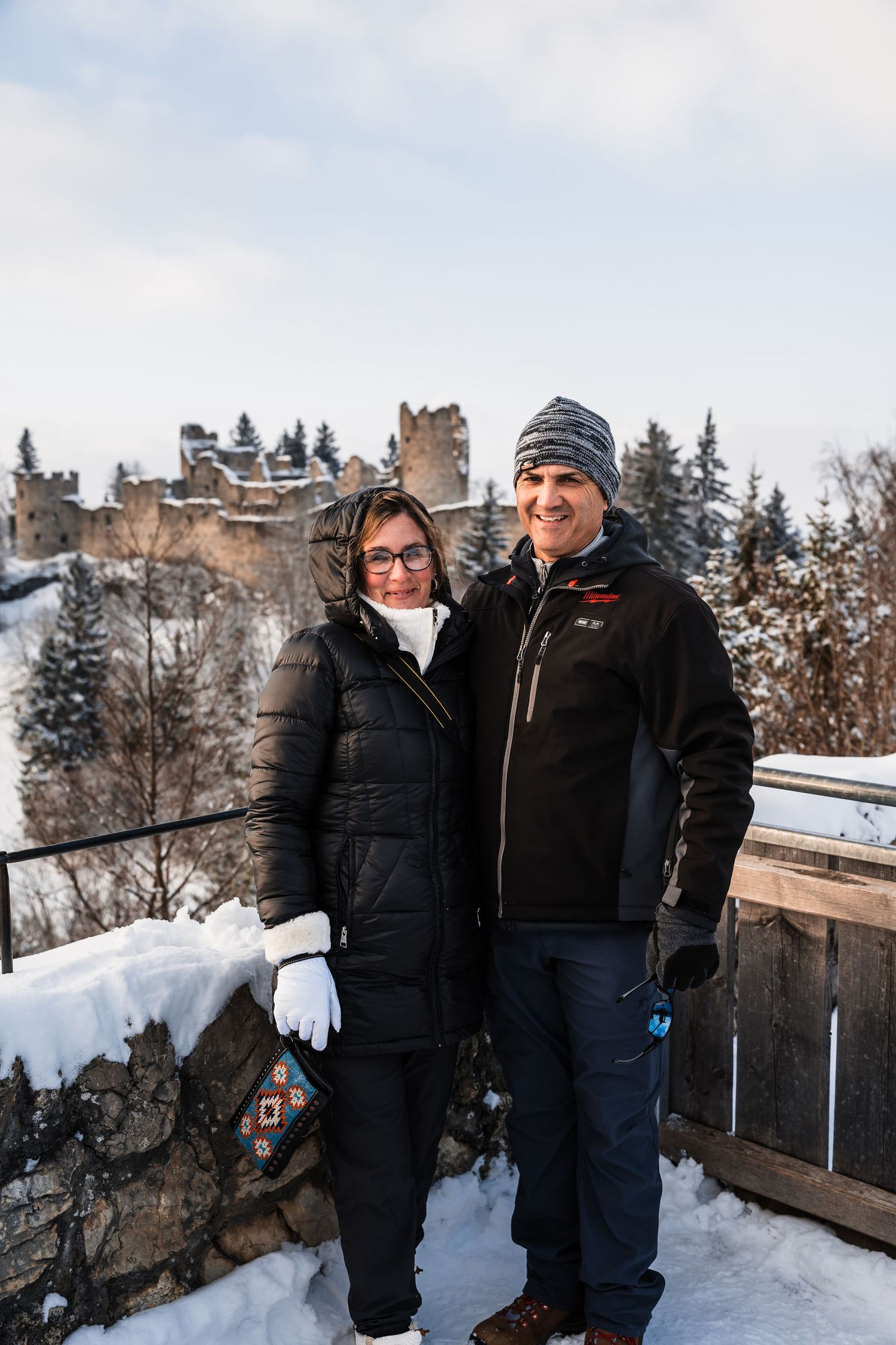 Visitors enjoying a snowy winter day at an ancient castle ruins site.
