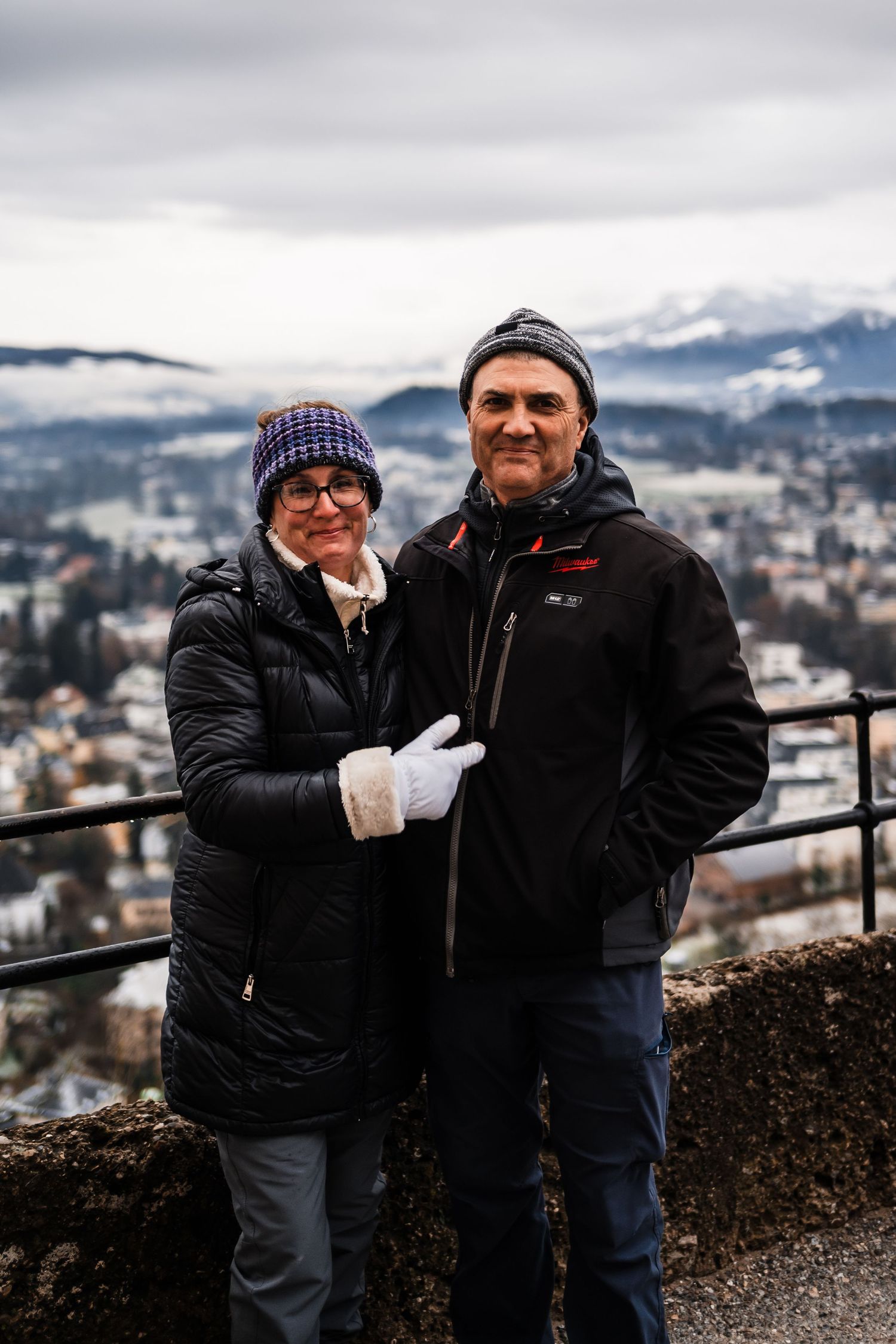 Snow-capped mountains and city buildings visible in the background of a scenic winter overlook.
