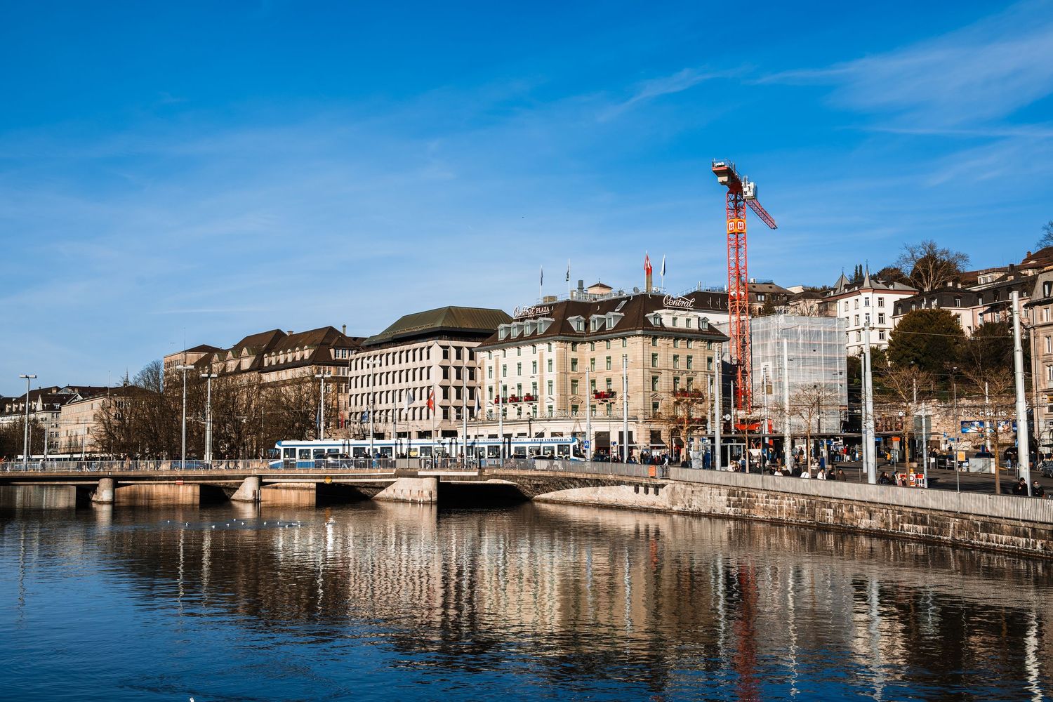 Panoramic view of historic buildings and boats along the waterfront in Bayonne, France under bright blue sky.