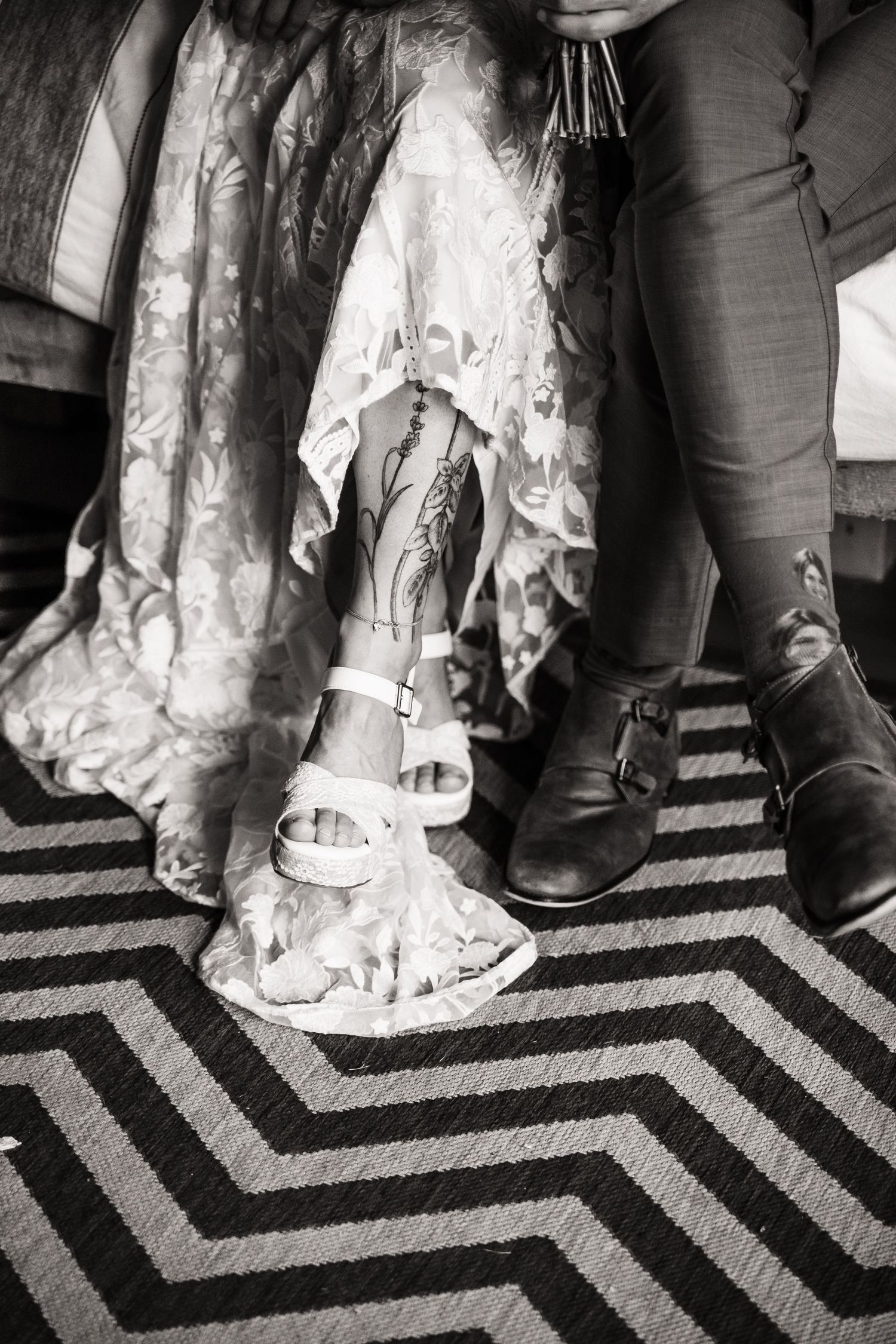 Black and white detail shot of wedding dress and shoes on chevron patterned carpet.