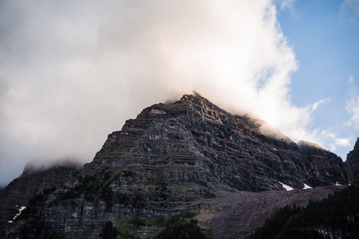 Rugged mountain peak emerging through dramatic clouds at sunset.