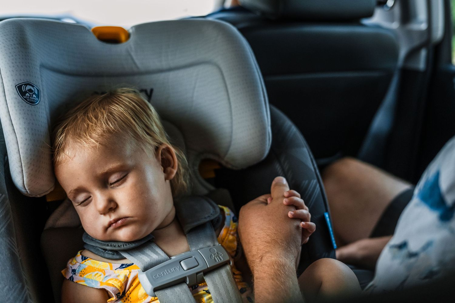 A young child sleeps peacefully in a car seat during a journey.