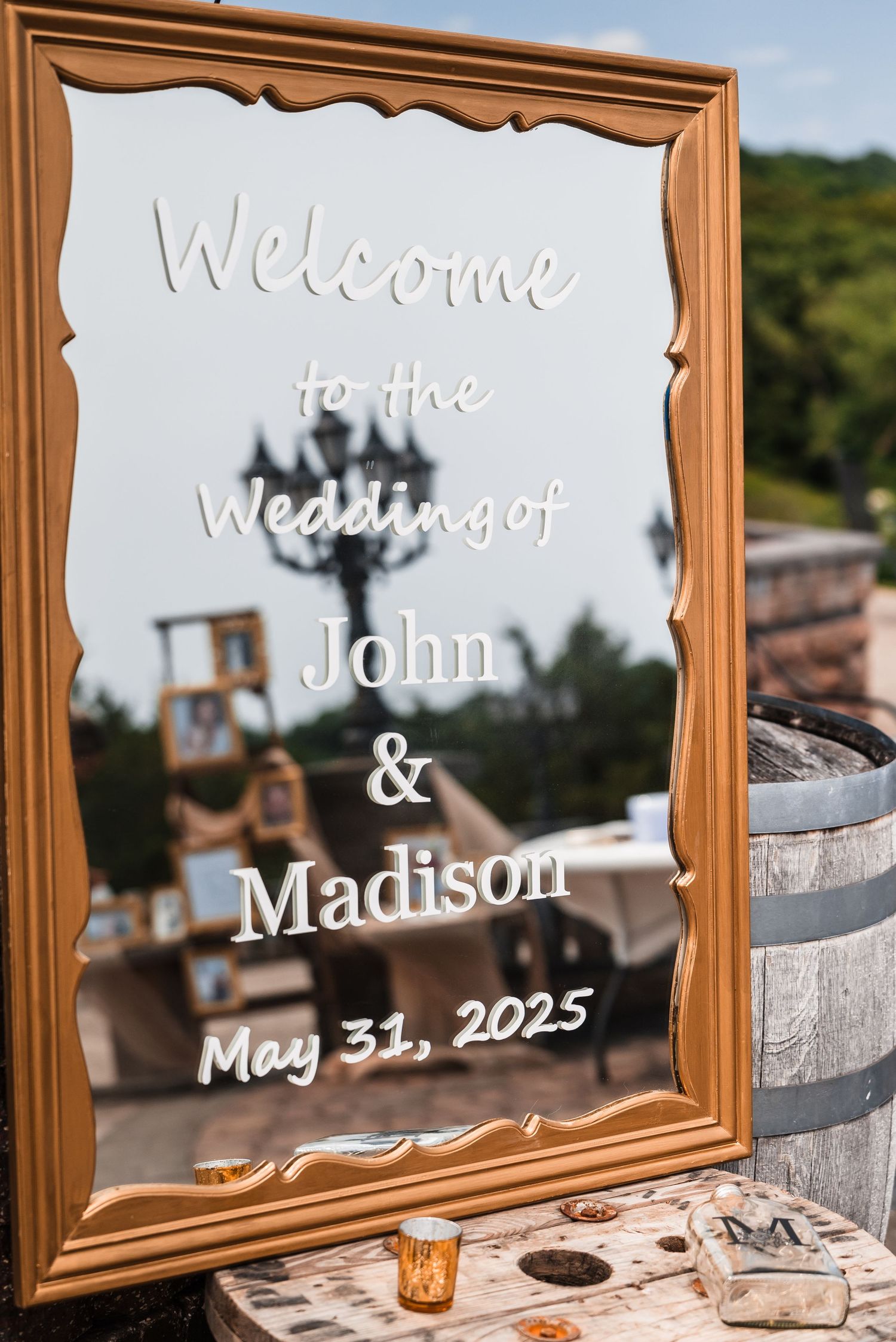 Wedding welcome sign with wooden frames and elegant calligraphy displayed at an outdoor venue.