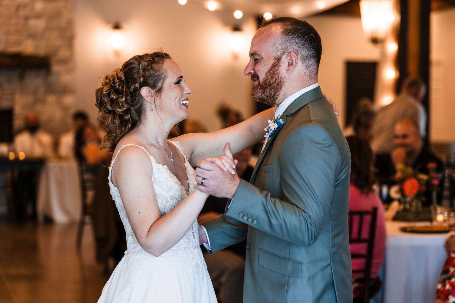 Bride and groom sharing a joyful first dance at their rustic wedding reception venue.