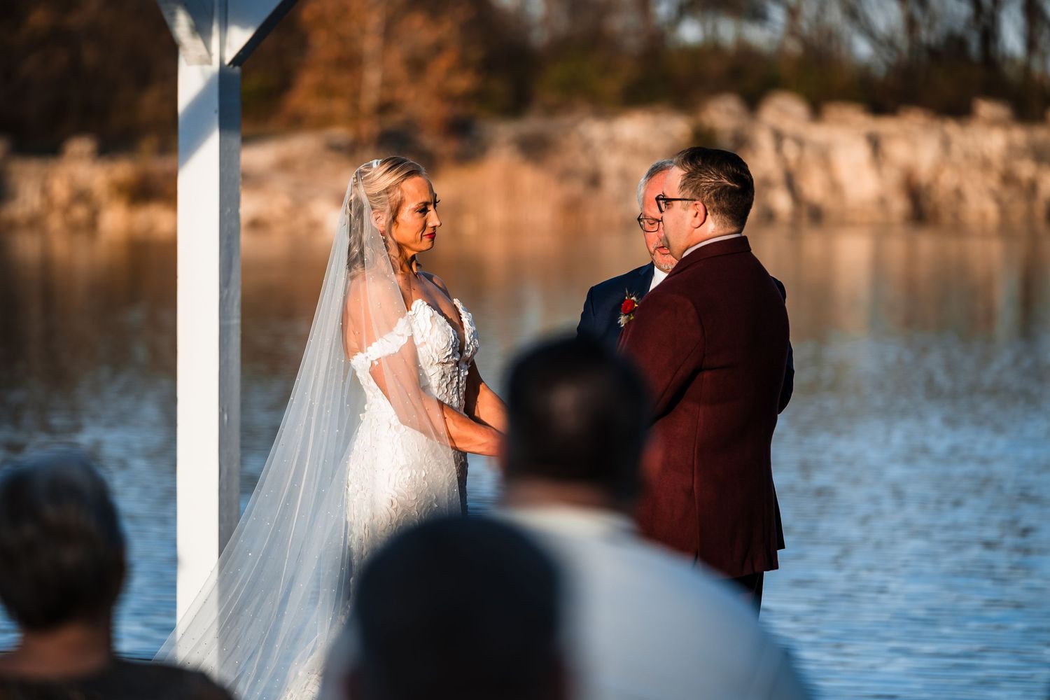 Outdoor wedding ceremony by a lake during golden hour.