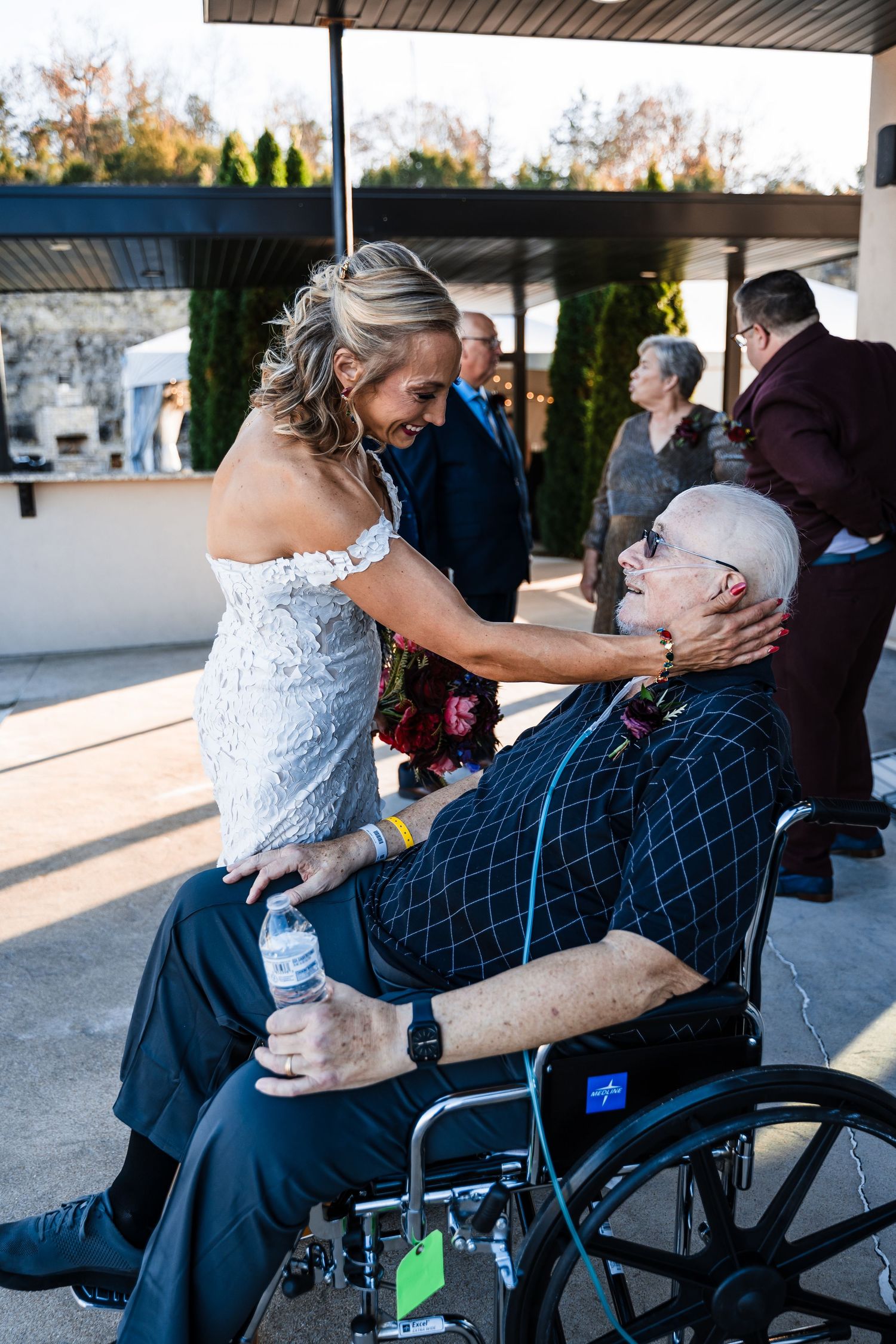 Emotional moments captured between wedding guests outside on a sunny day.