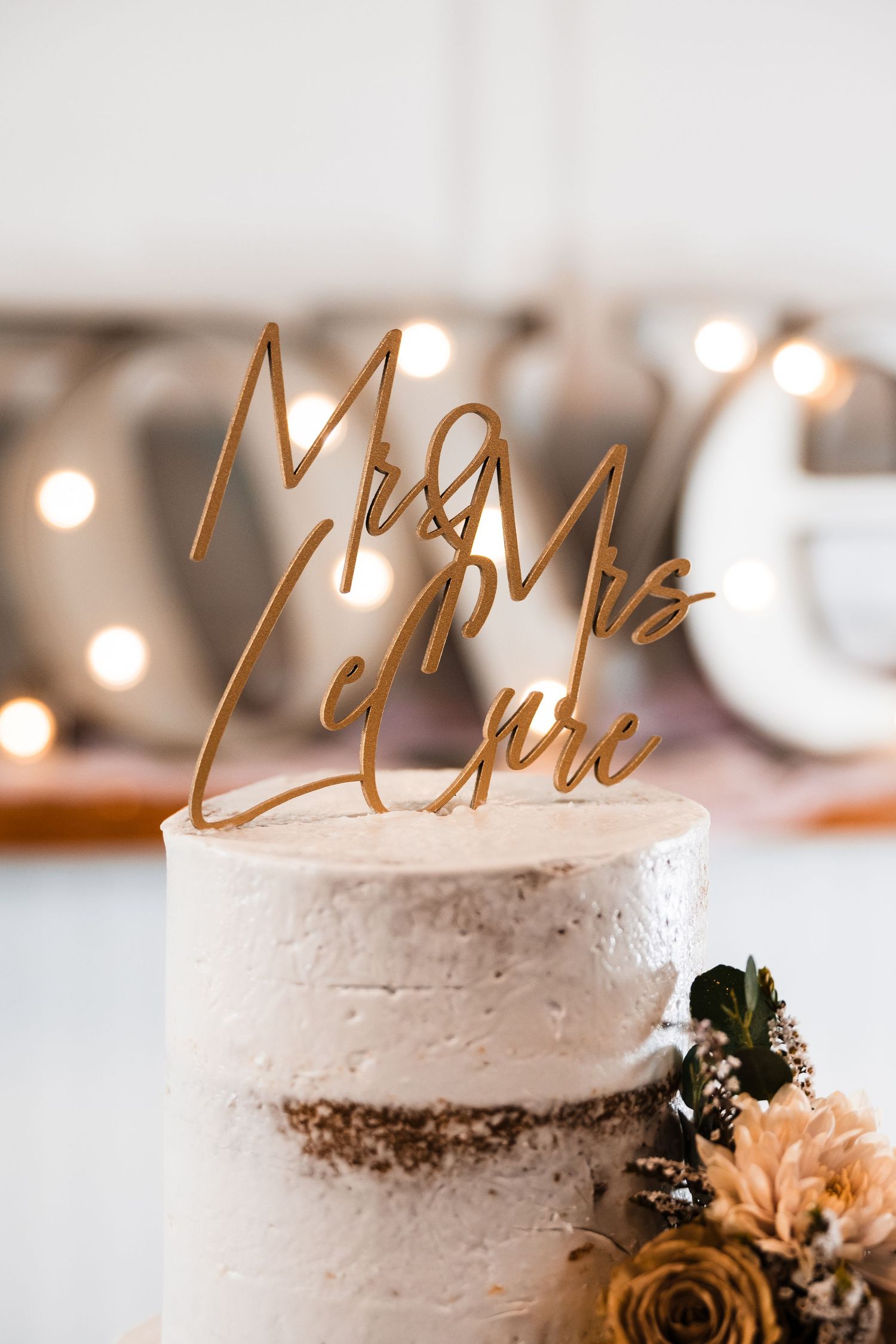 Close-up of white wedding cake with gold metallic topper decoration.