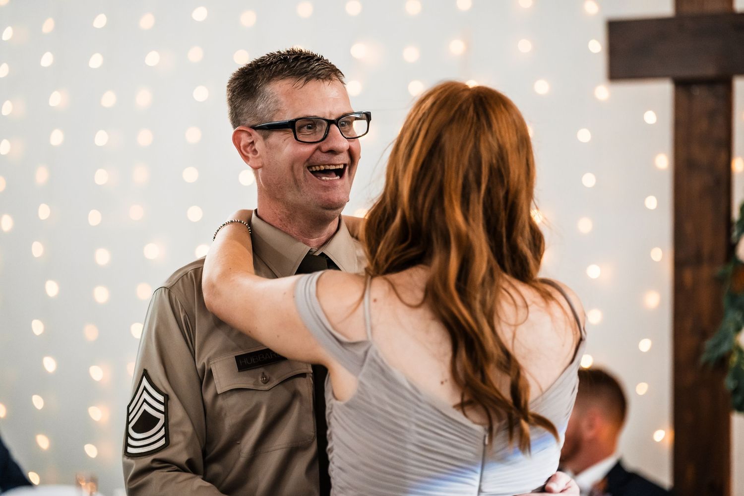 Couple dancing and laughing together at a reception with string lights decorating the background.