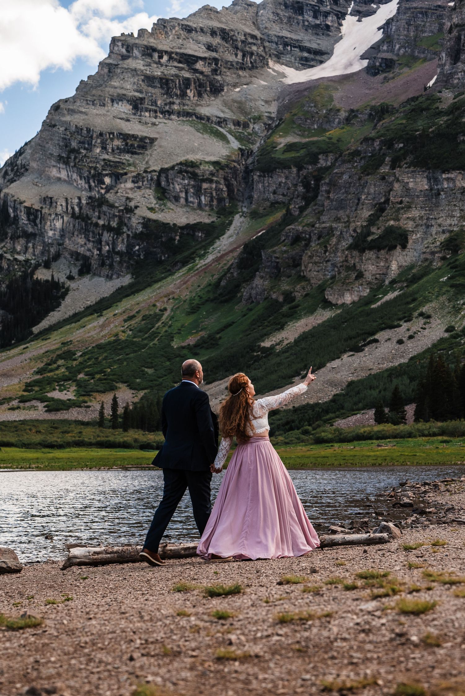 Couple admiring majestic mountain views beside an alpine lake.