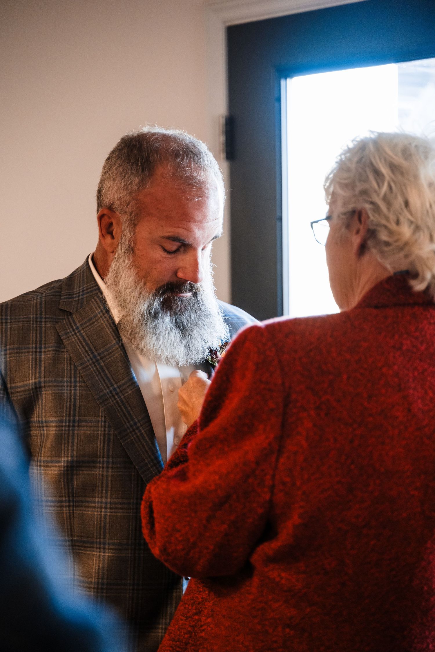 Two people in formal attire having an intimate conversation by a window.