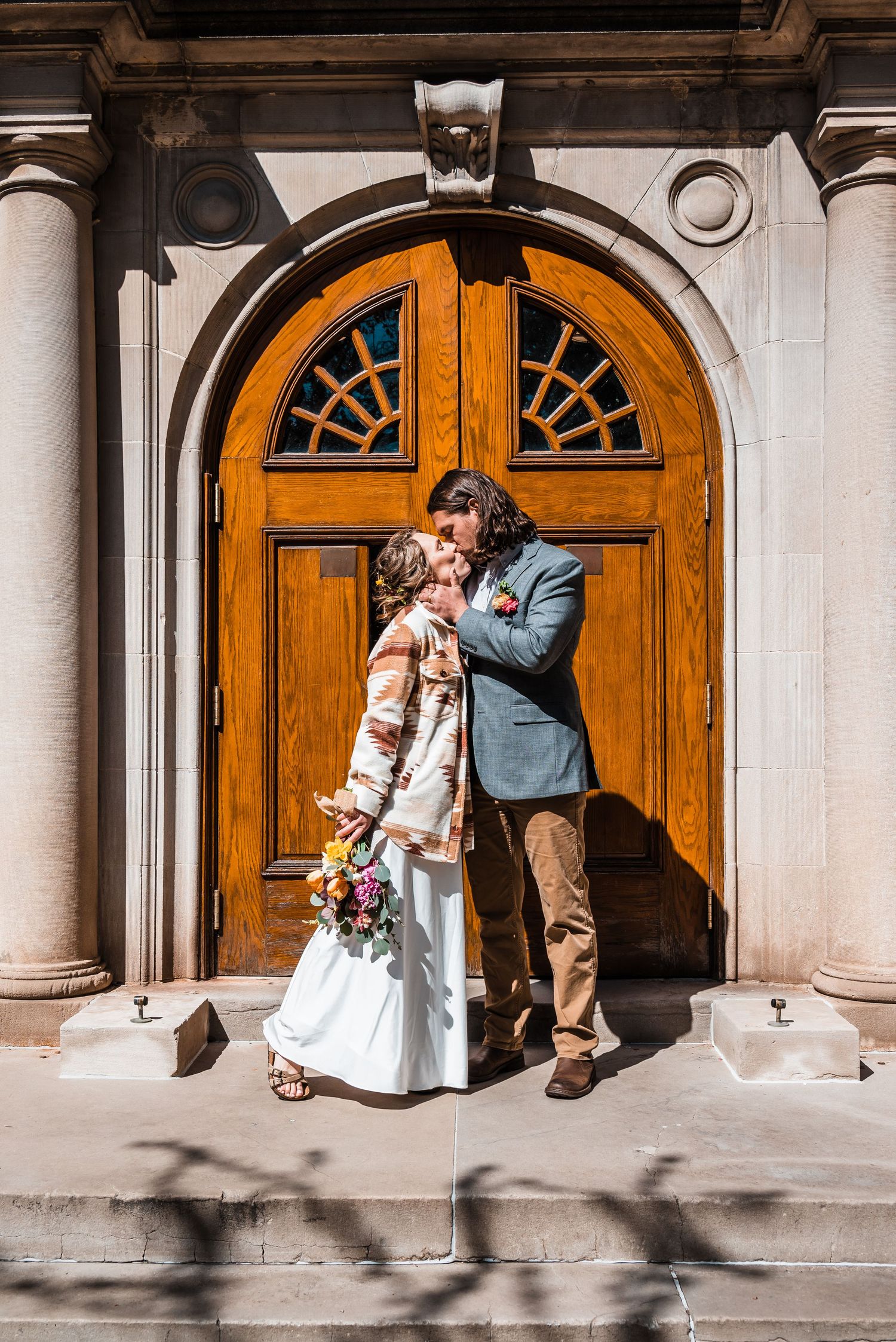 A couple embraces near an ornate wooden door during their wedding portraits.