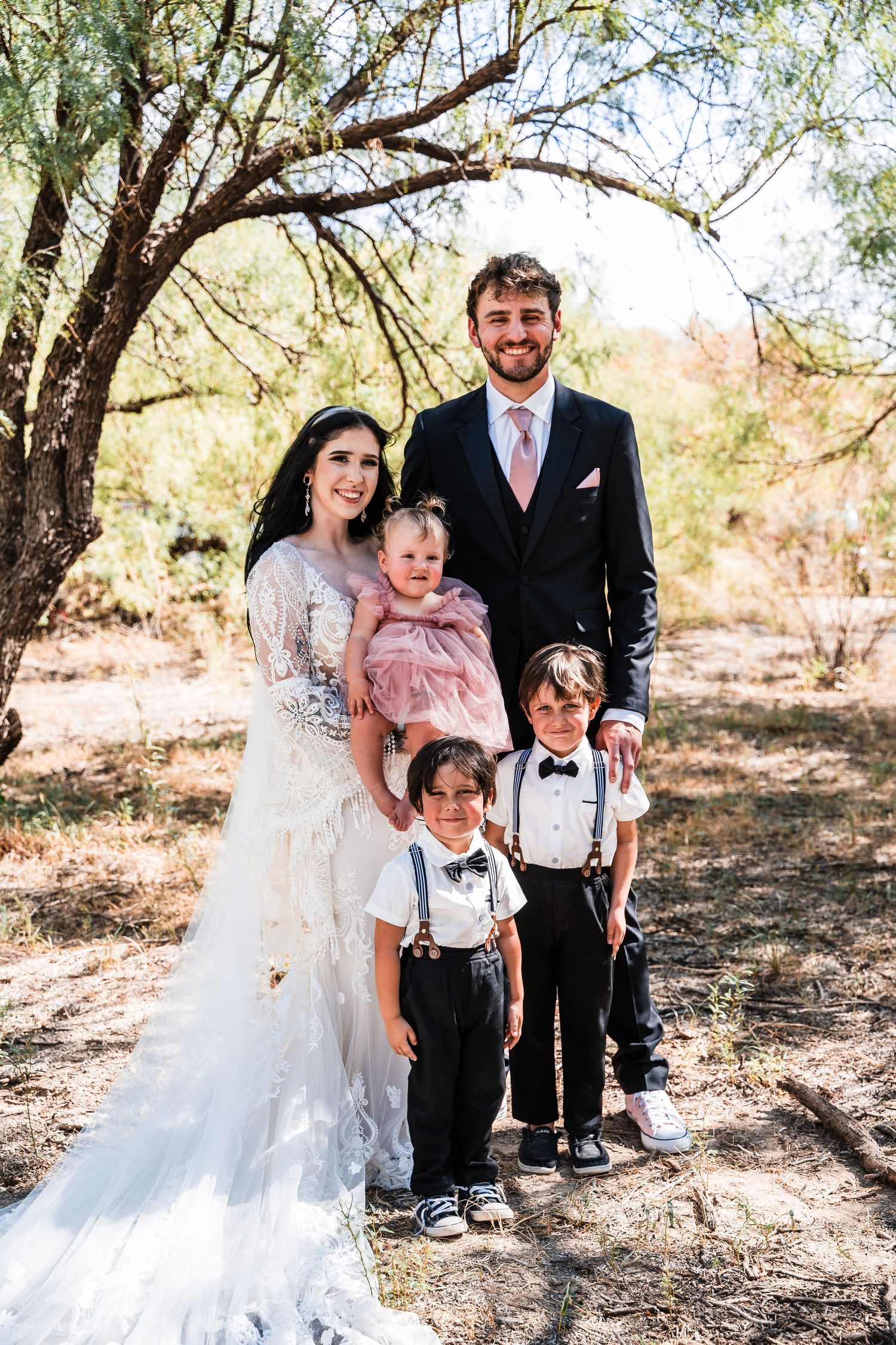Wedding photo showing a couple with three children under a desert tree.