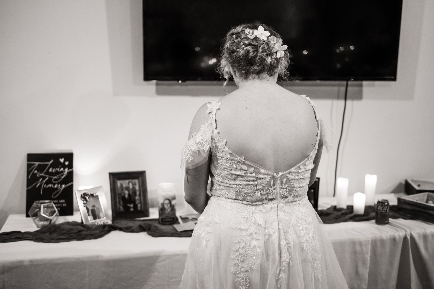 Back view of a bride in a detailed lace wedding dress standing near a decorated table.