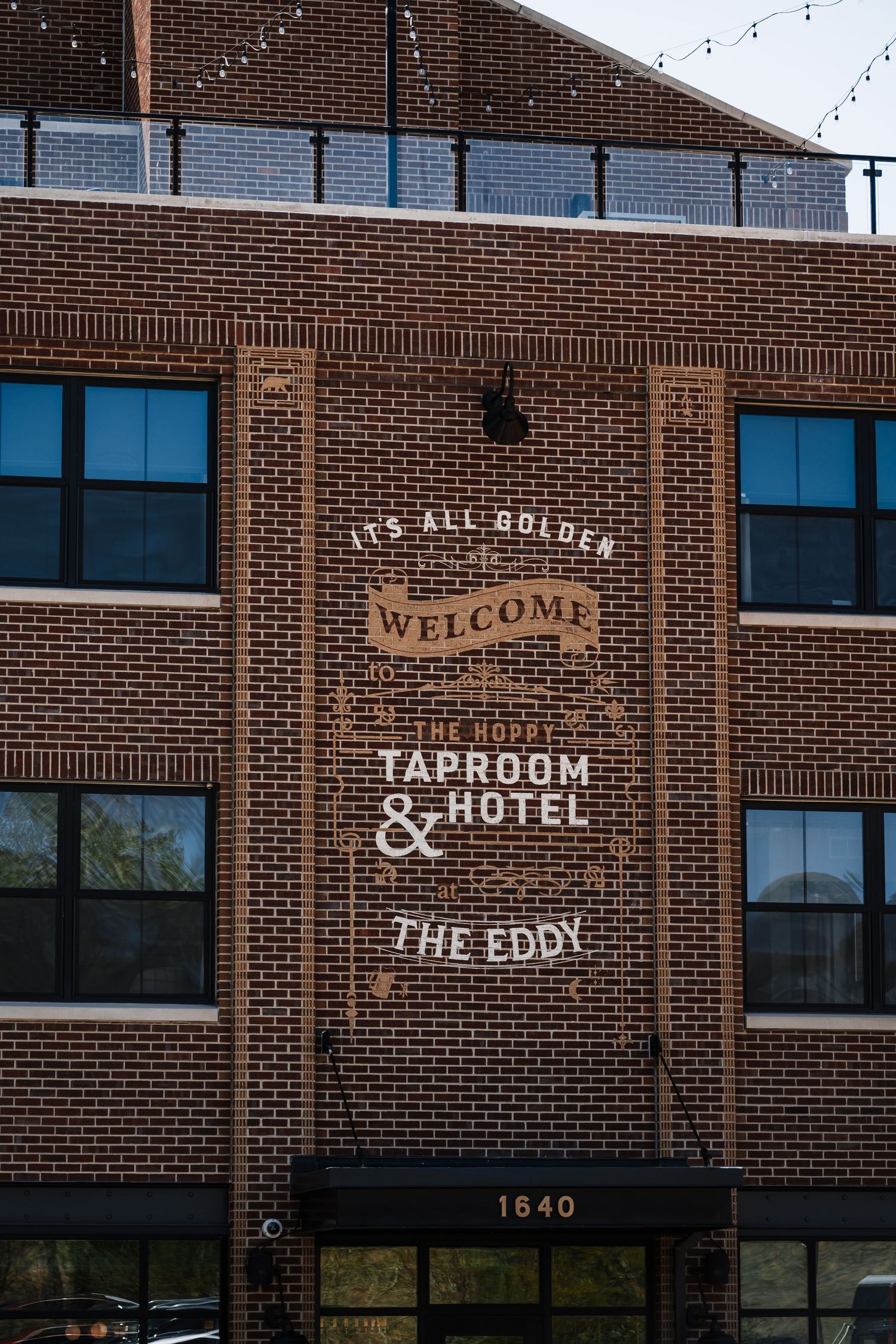 Brick exterior of The Hoppy Taproom and Hotel The Eddy at 1640 with welcome signage.