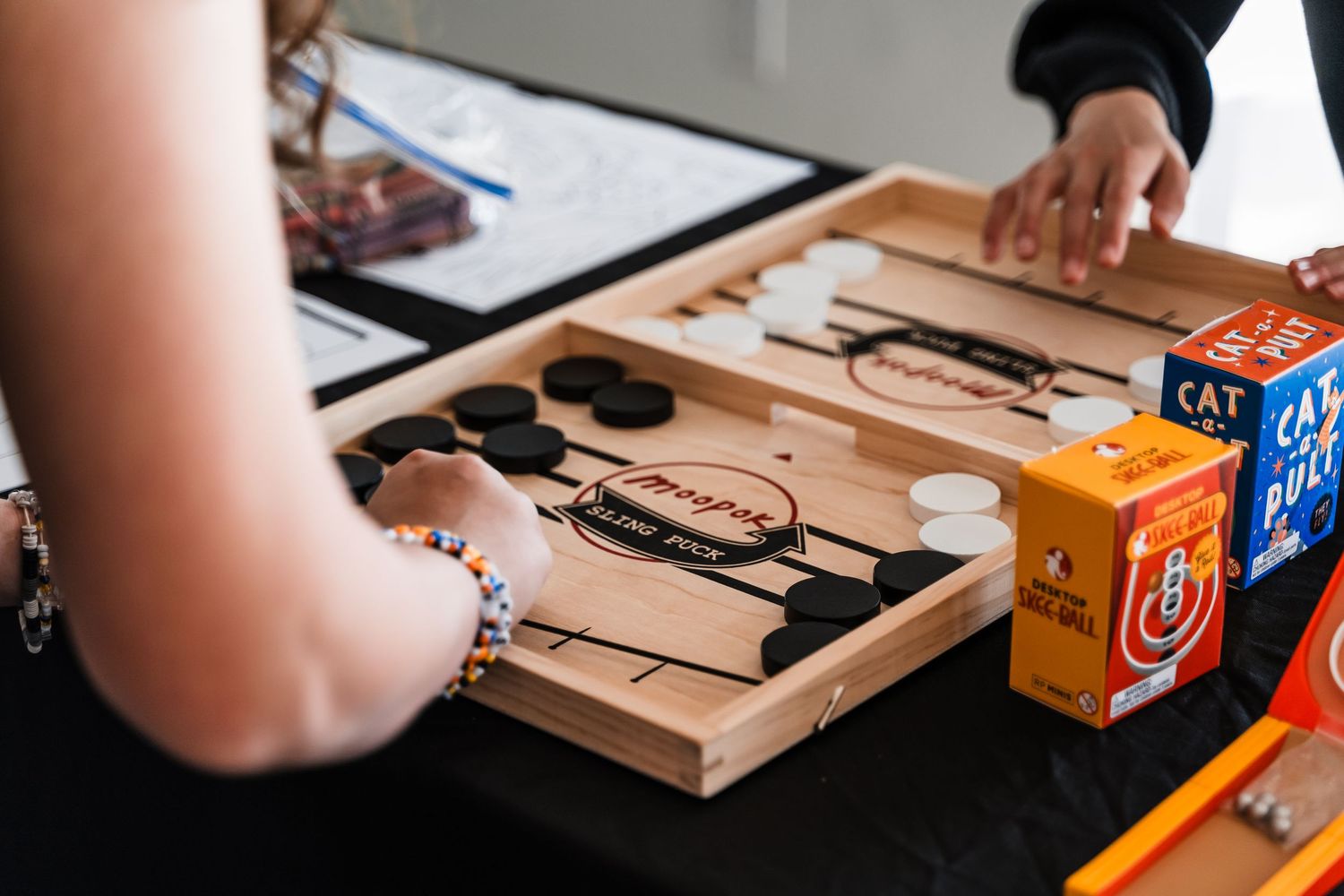 Players enjoy a custom engraved backgammon board game on a black table at a party.