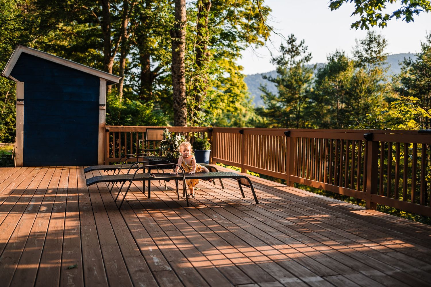 Wooden deck with patio furniture overlooking a scenic forested mountain landscape.