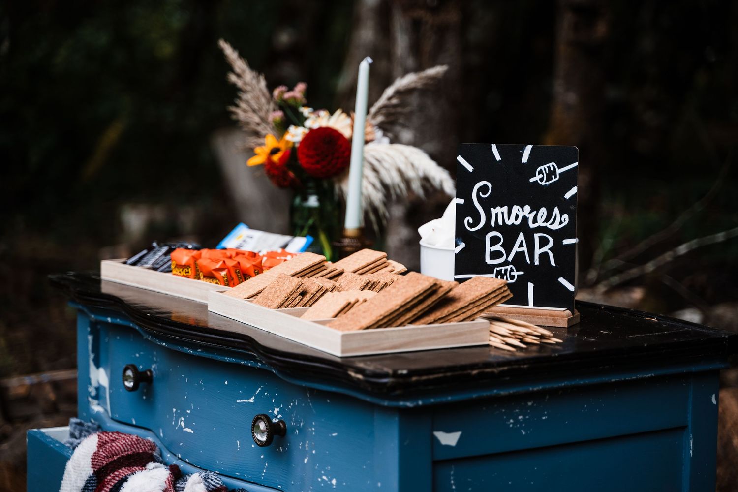 A rustic blue snack bar setup with wooden cutting boards and orange garnishes.