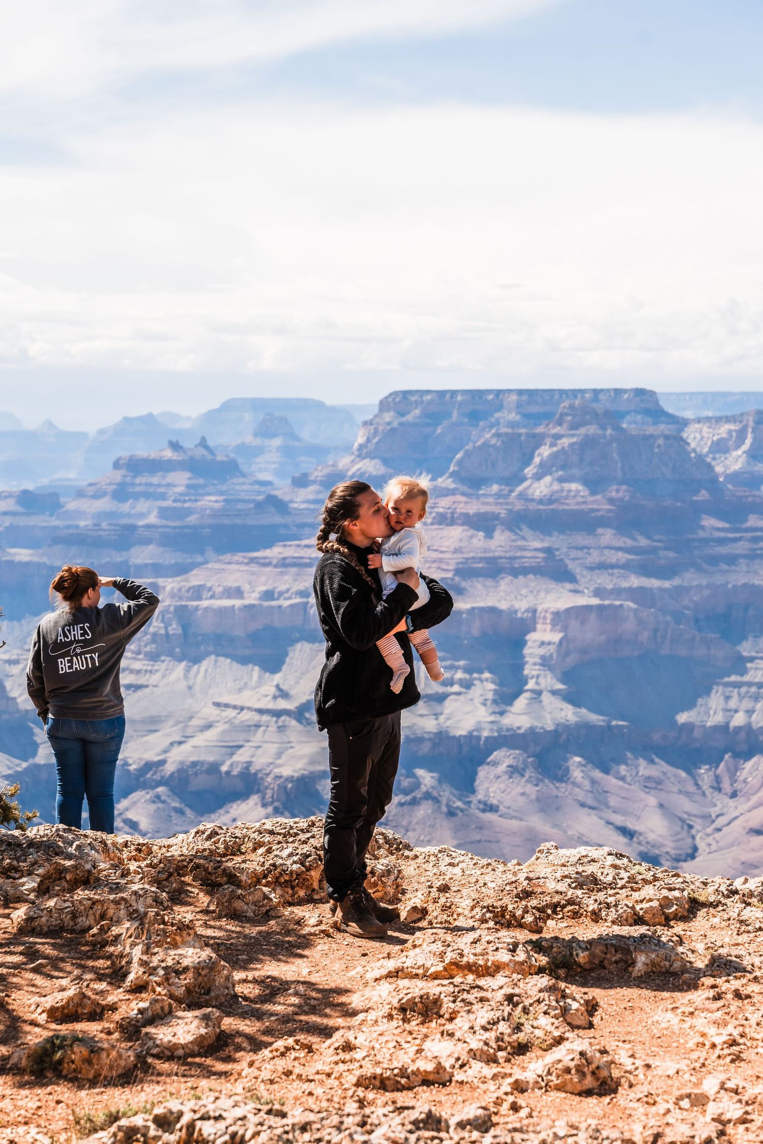 Visitors stand at the Grand Canyon's edge enjoying panoramic views of the vast desert landscape.