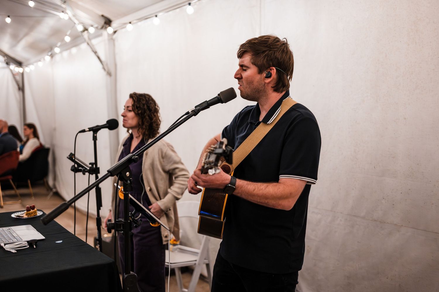 Musicians performing at an indoor wedding reception with white backdrop.