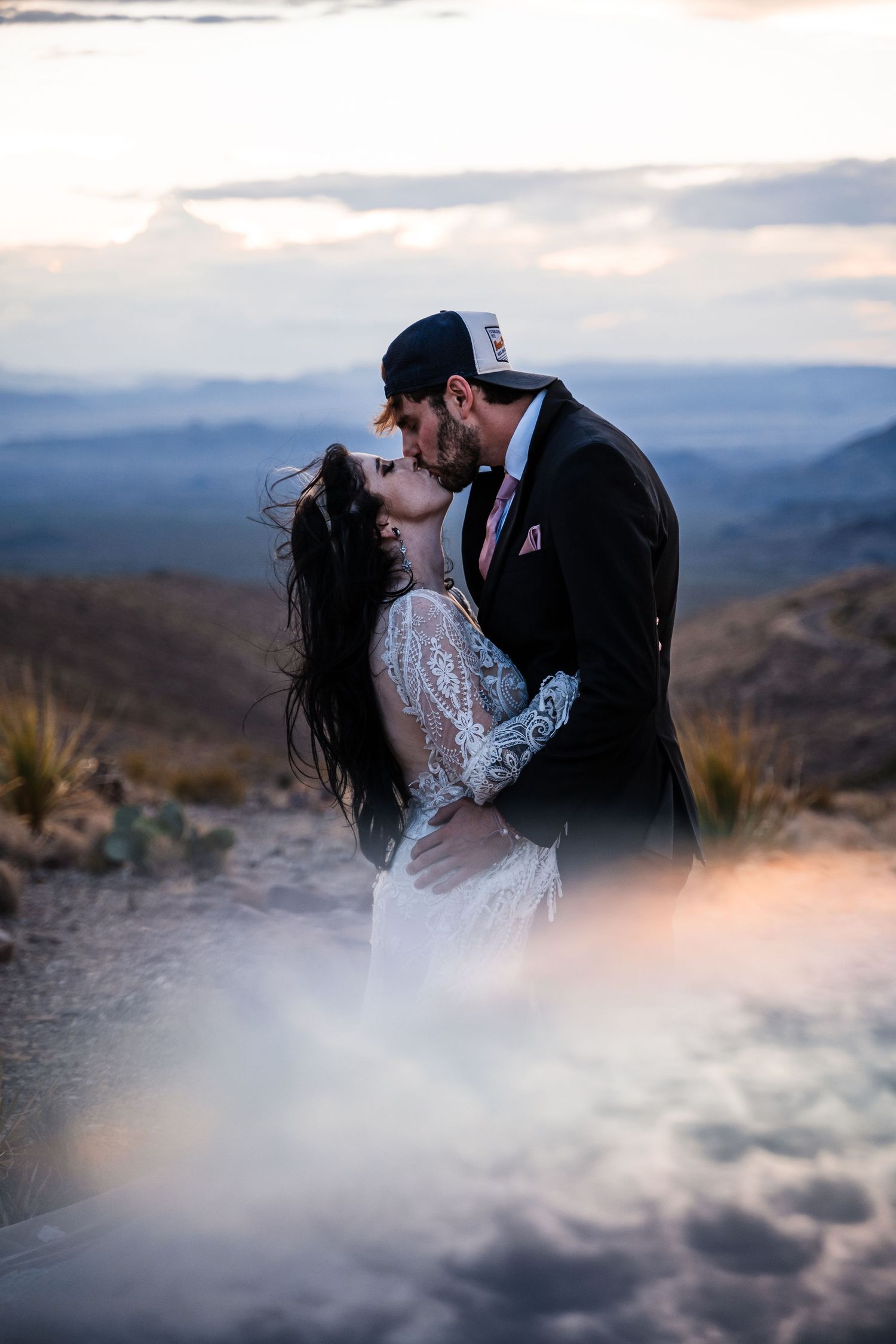 Dramatic mountain landscape with couple sharing intimate moment in misty conditions.