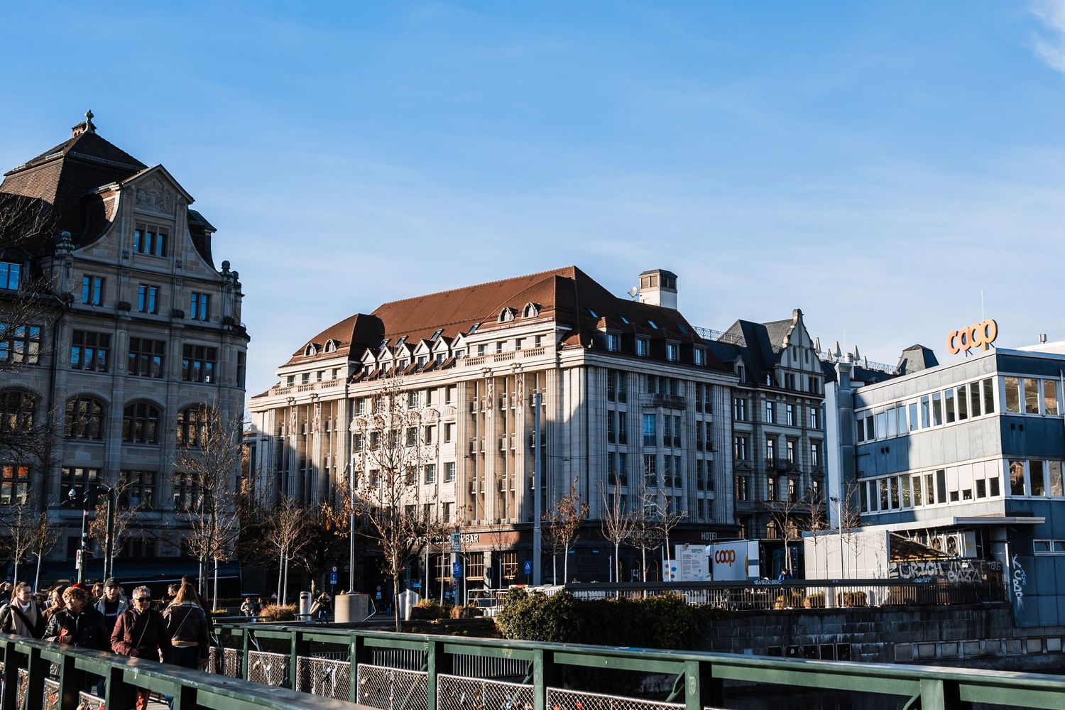 Historic European buildings line a city street with ornate architecture and traditional design elements in daylight.