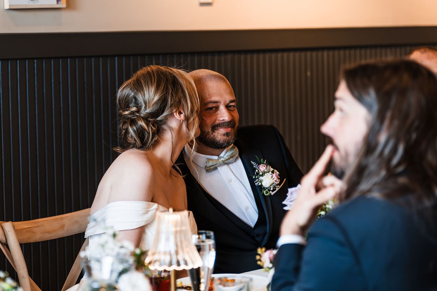 Bride and groom sharing an intimate laughing moment together at wedding reception dinner table.