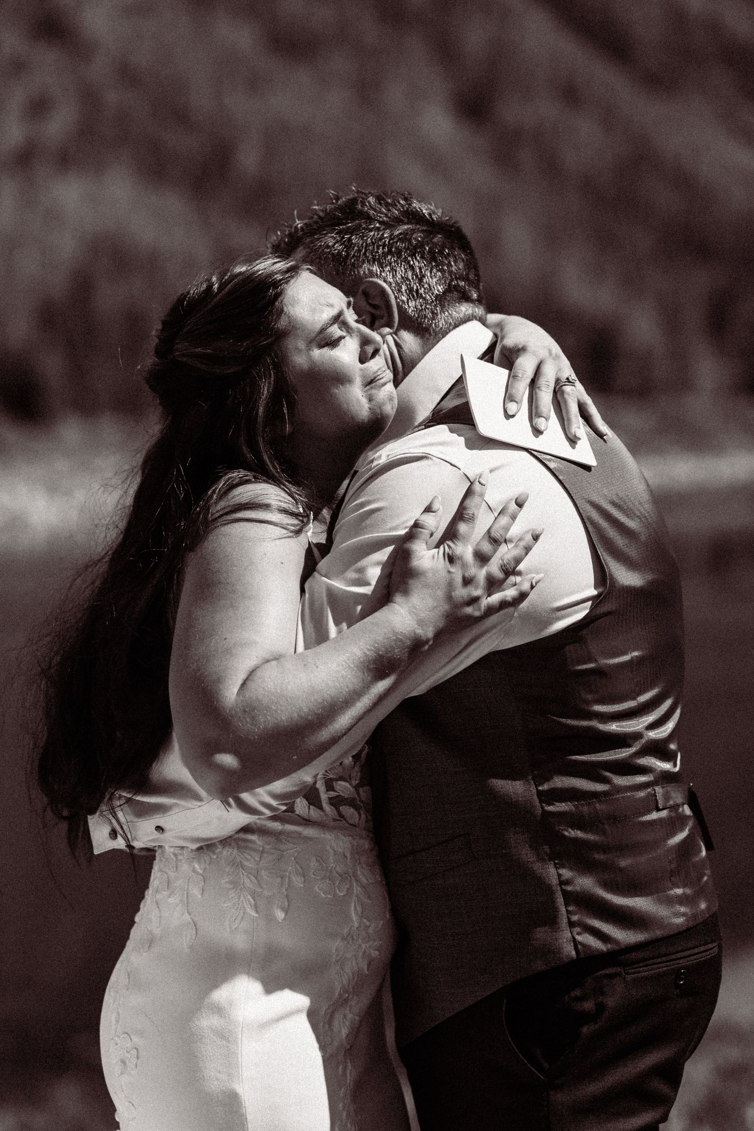 Black and white photo of bride and groom sharing a heartfelt embrace during their outdoor mountain wedding.