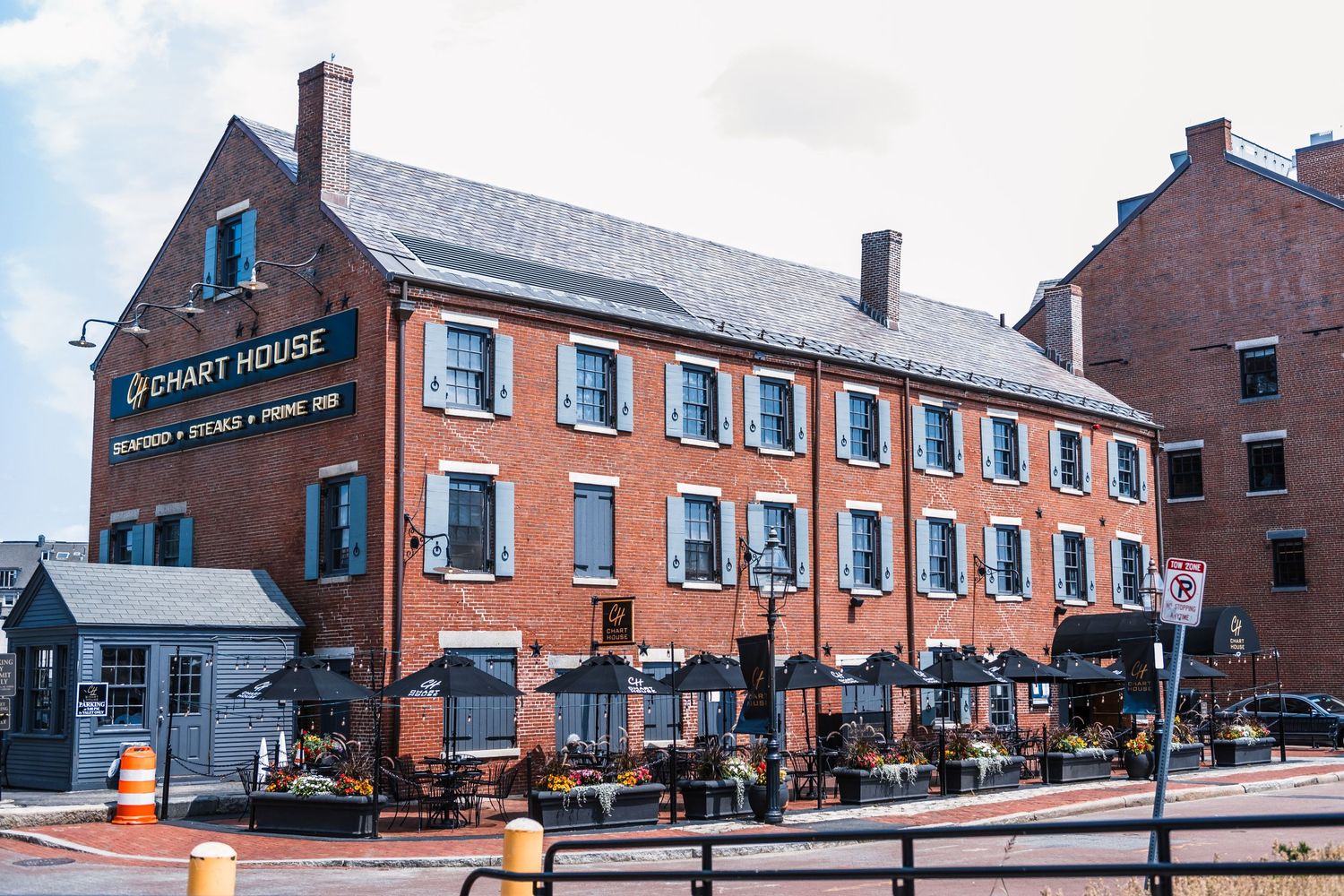 Historic red brick waterfront building with shuttered windows and outdoor seating along Portland's Commercial Street.