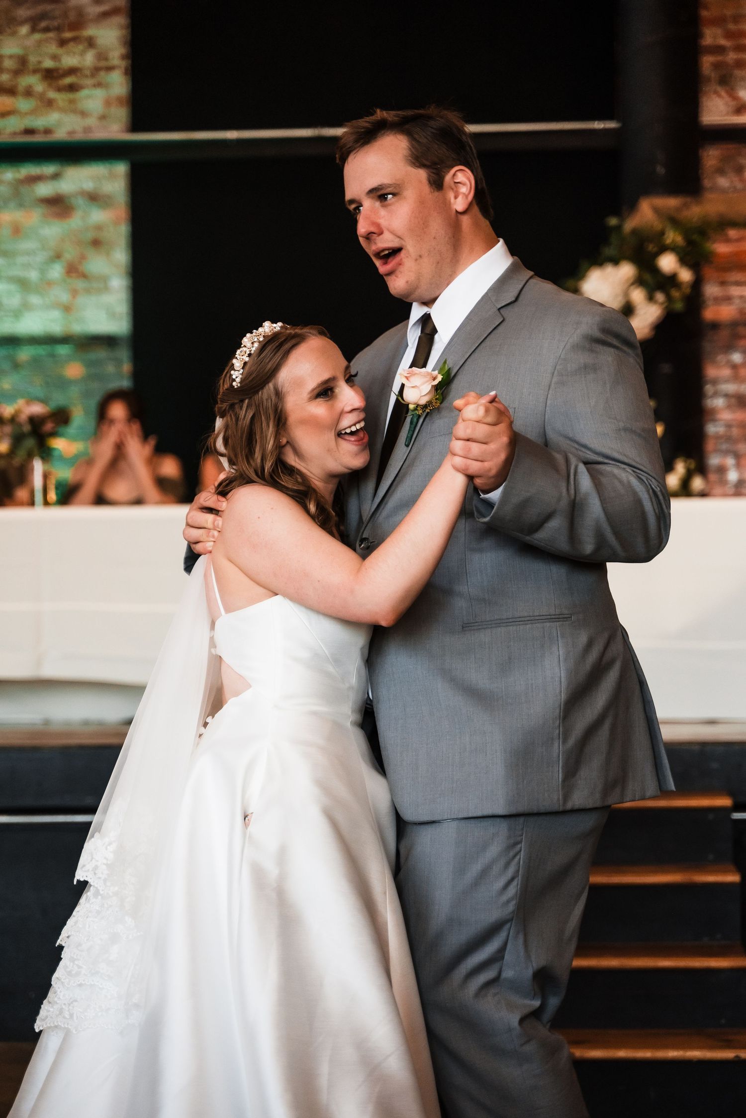 A couple dances together during their wedding reception in a rustic industrial venue.