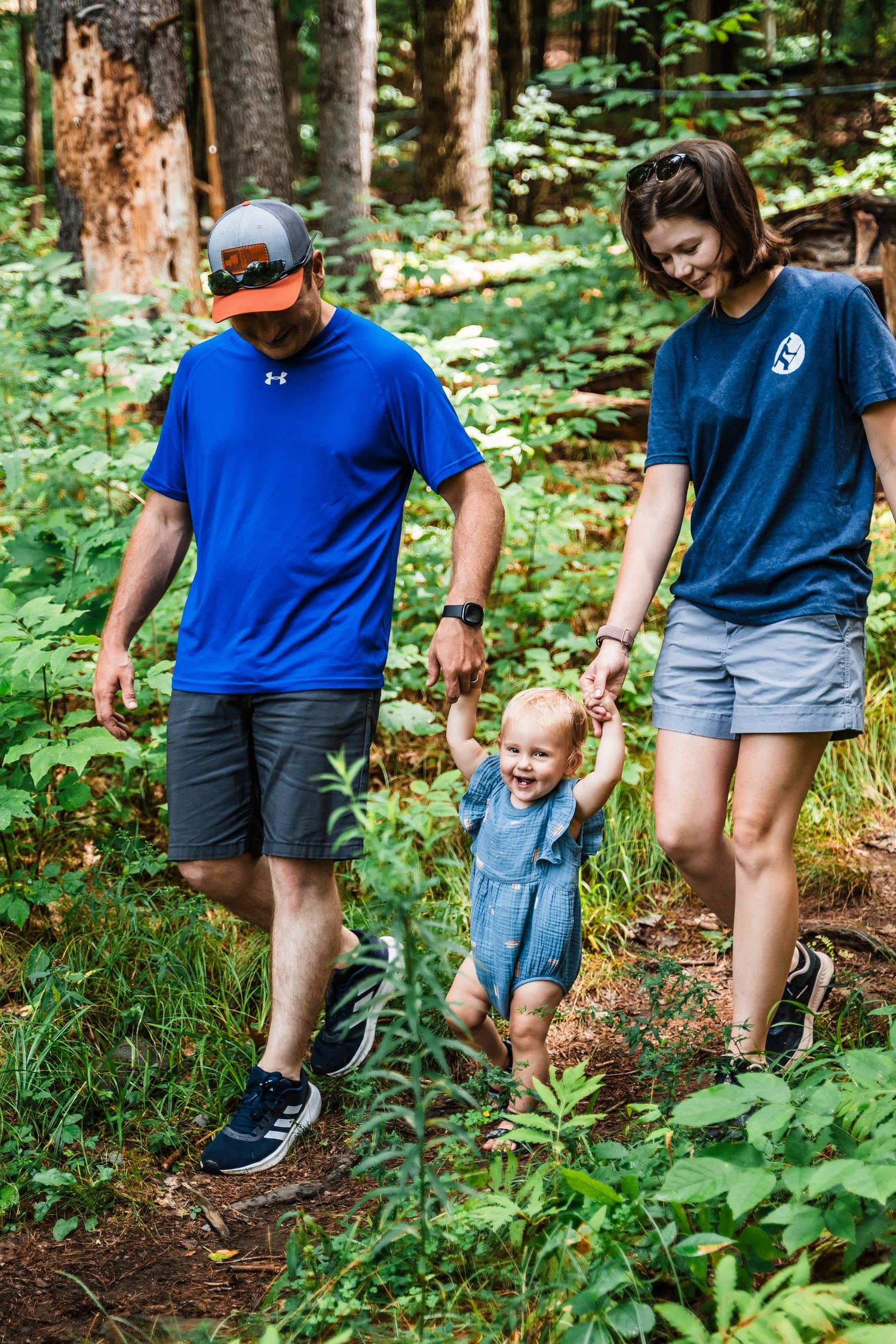 A family enjoys a nature walk together along a wooded trail in summer.