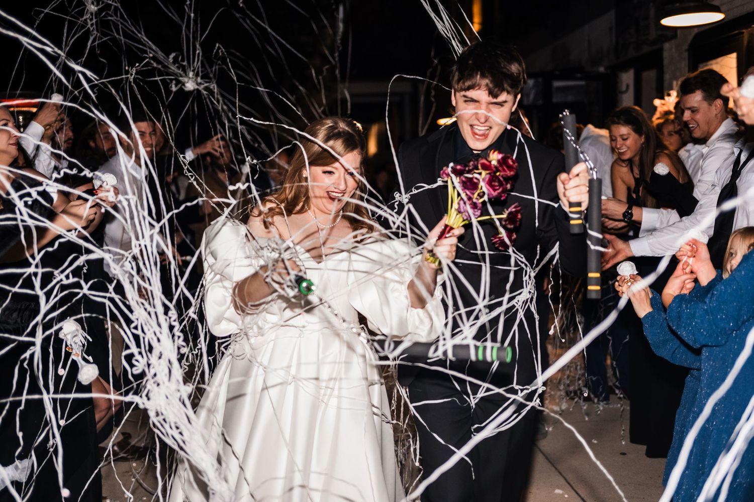 Newlyweds surrounded by streaming white party streamers during their wedding celebration.