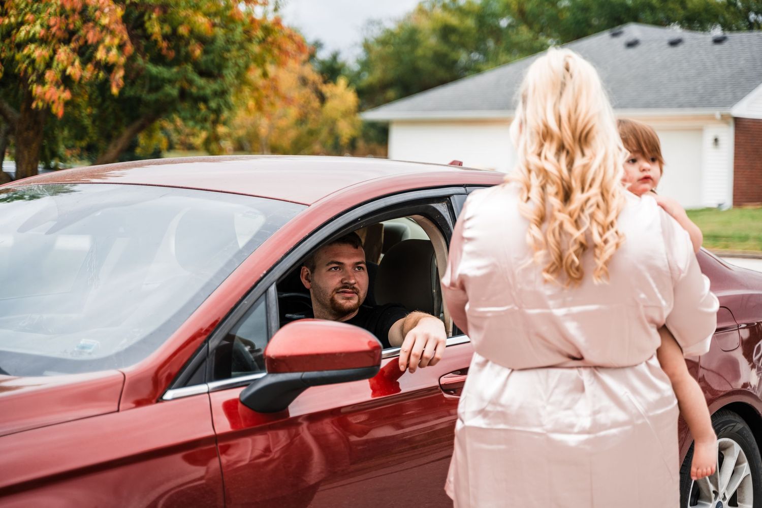 Cheerful interaction through car window during wedding day departure.