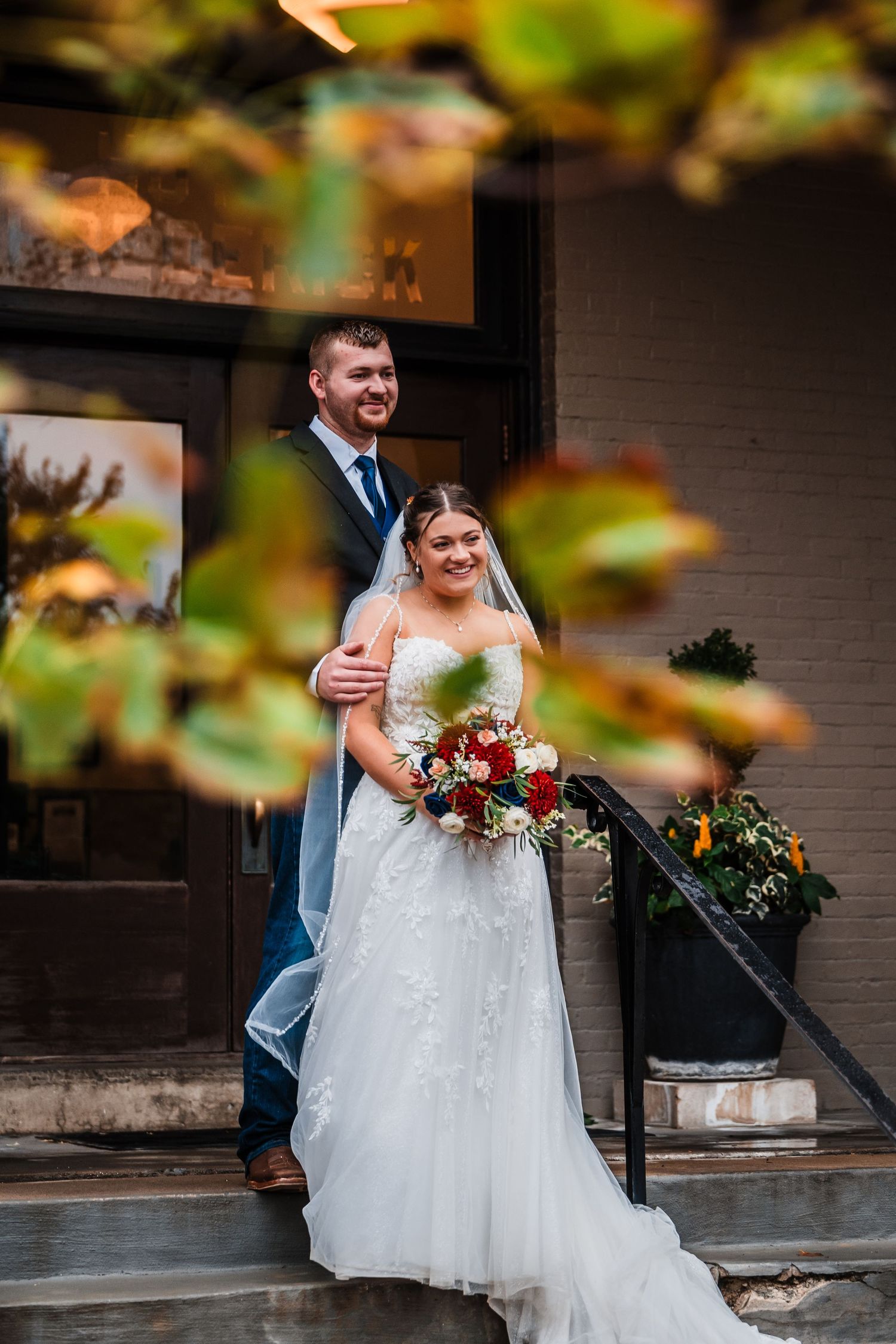Bride in white dress and groom walking together on outdoor steps.