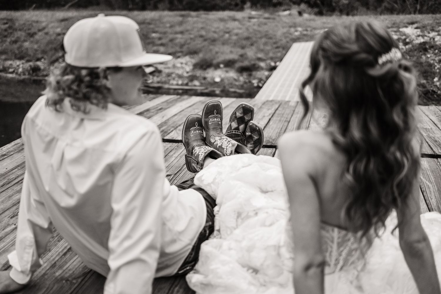 A black and white photograph shows two people sitting and toasting drinks together outdoors.