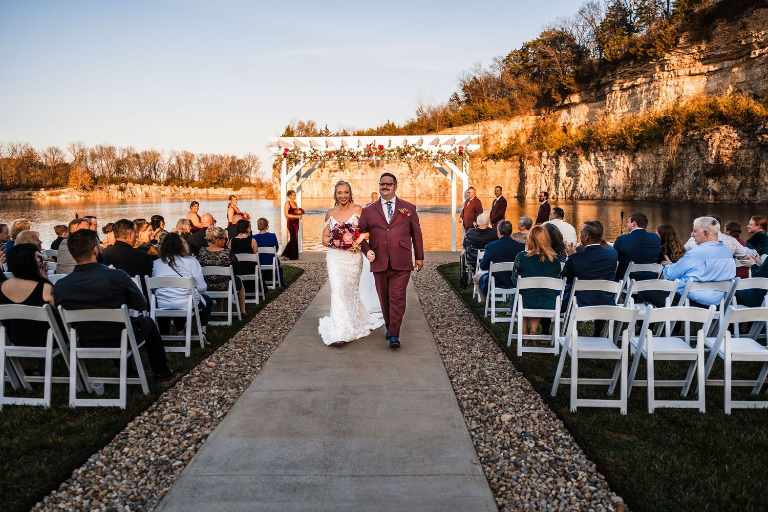 Wide shot of wedding ceremony setup with white chairs overlooking a scenic lake.