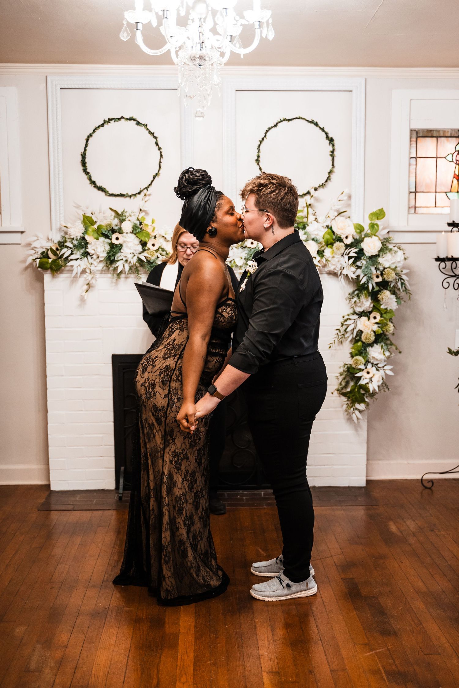 A romantic wedding moment captured in front of white doors adorned with floral wreaths.