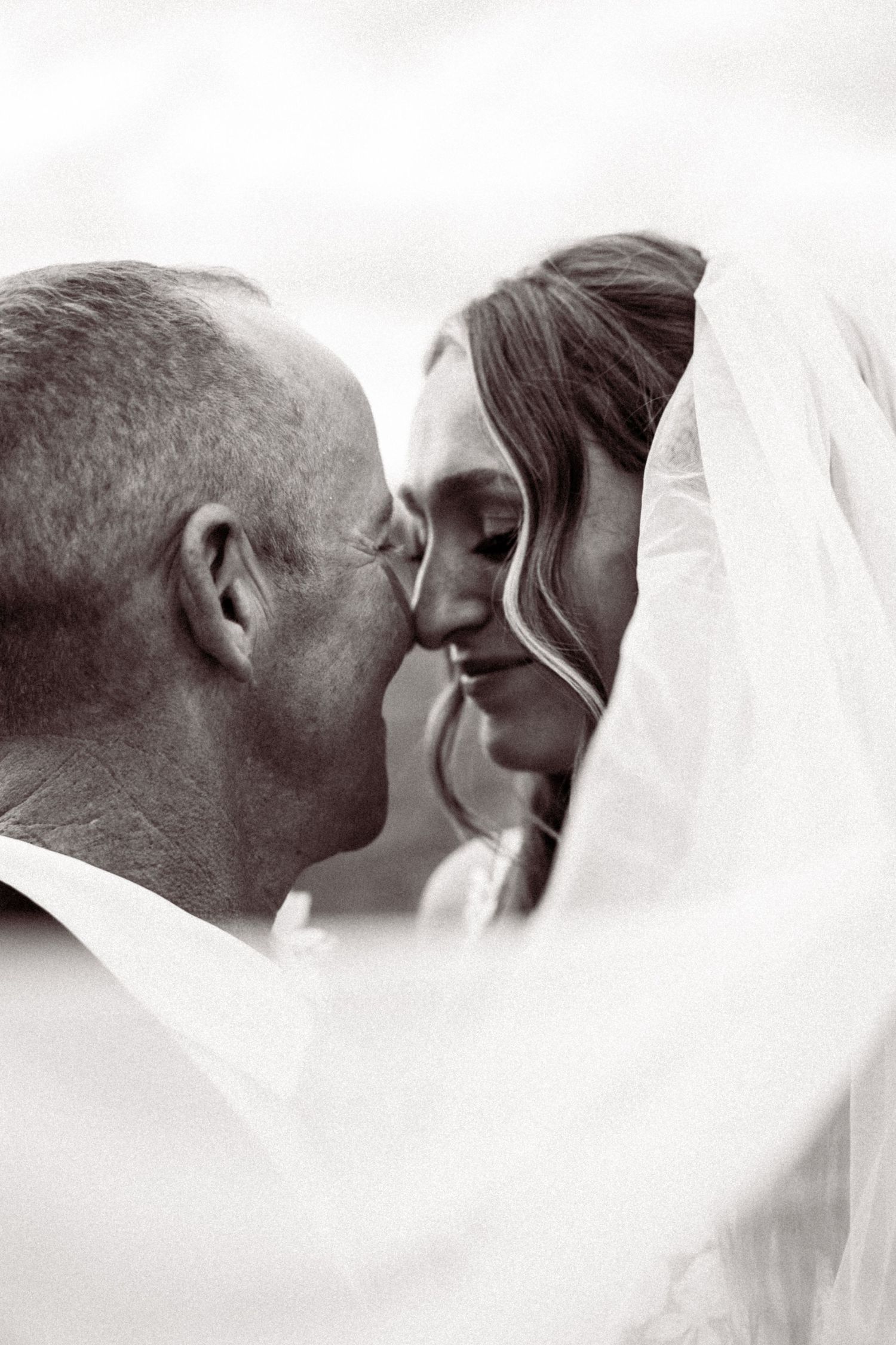 Intimate black and white portrait sequence of newlyweds sharing a tender moment under veil.