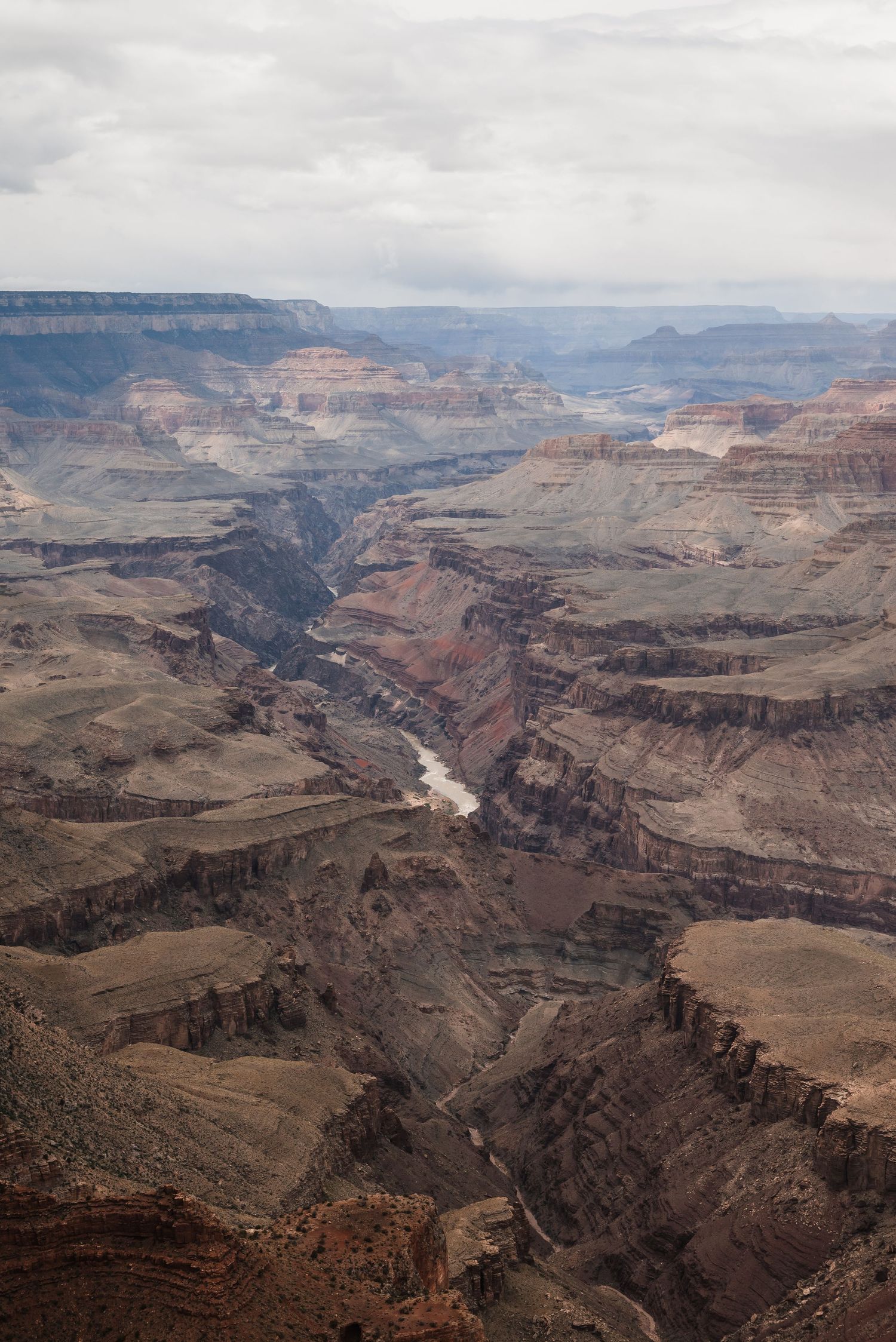 Deep canyon view showing the winding Colorado River cutting through layered rock formations of the Grand Canyon.