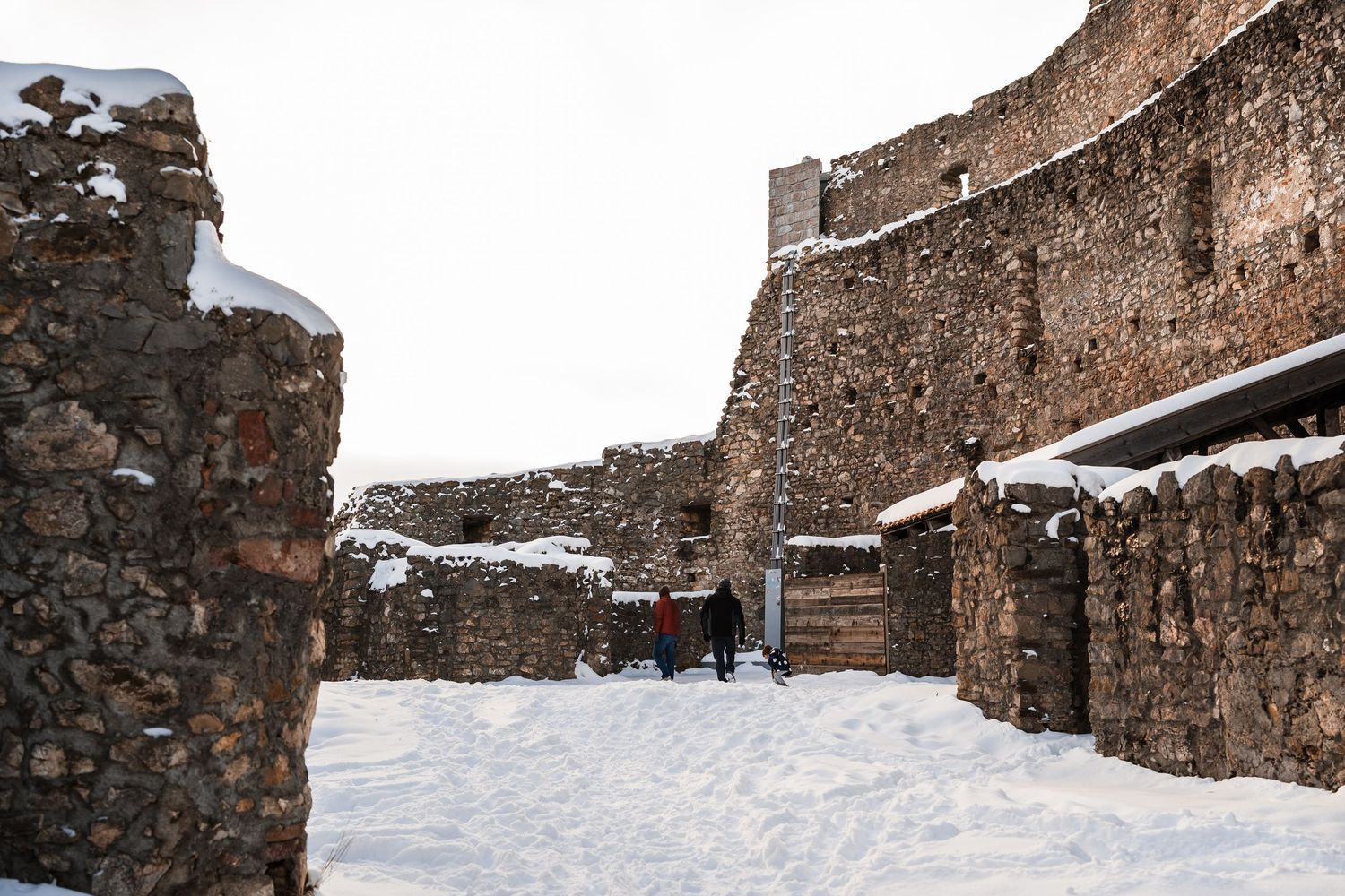 Snow-covered stone walls and walkways of a historic fortress with visitors exploring in winter.