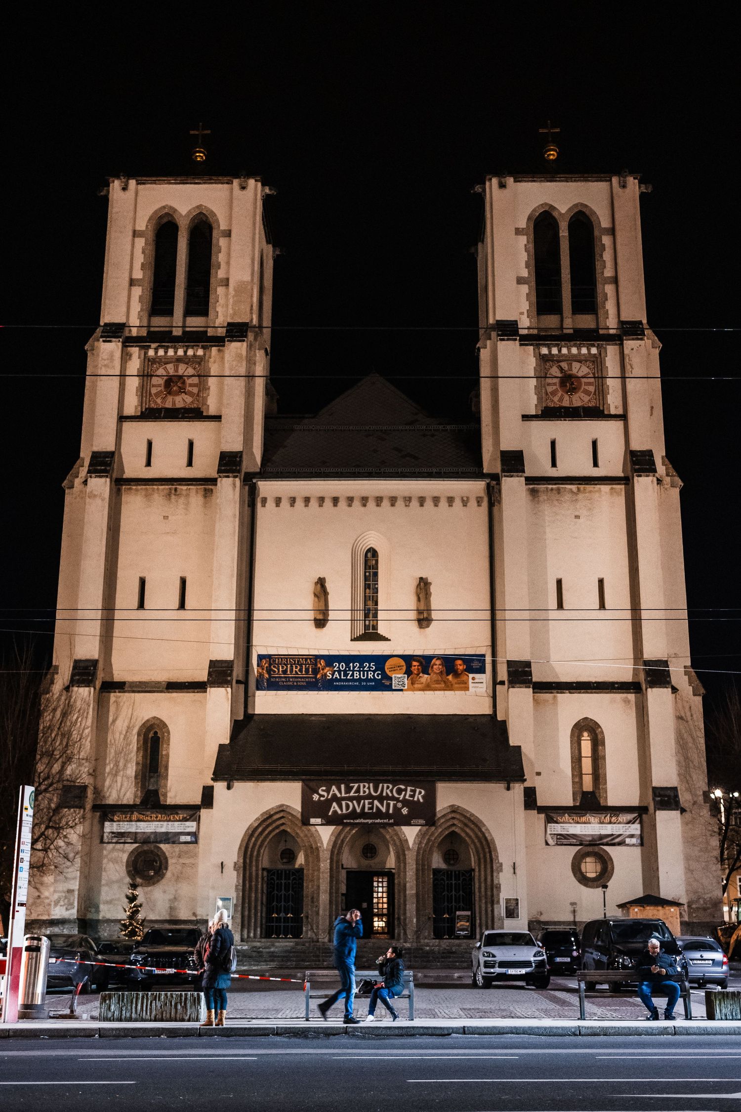 Historic church facade with twin towers photographed at different times showing people walking past in Salzburg, Austria.