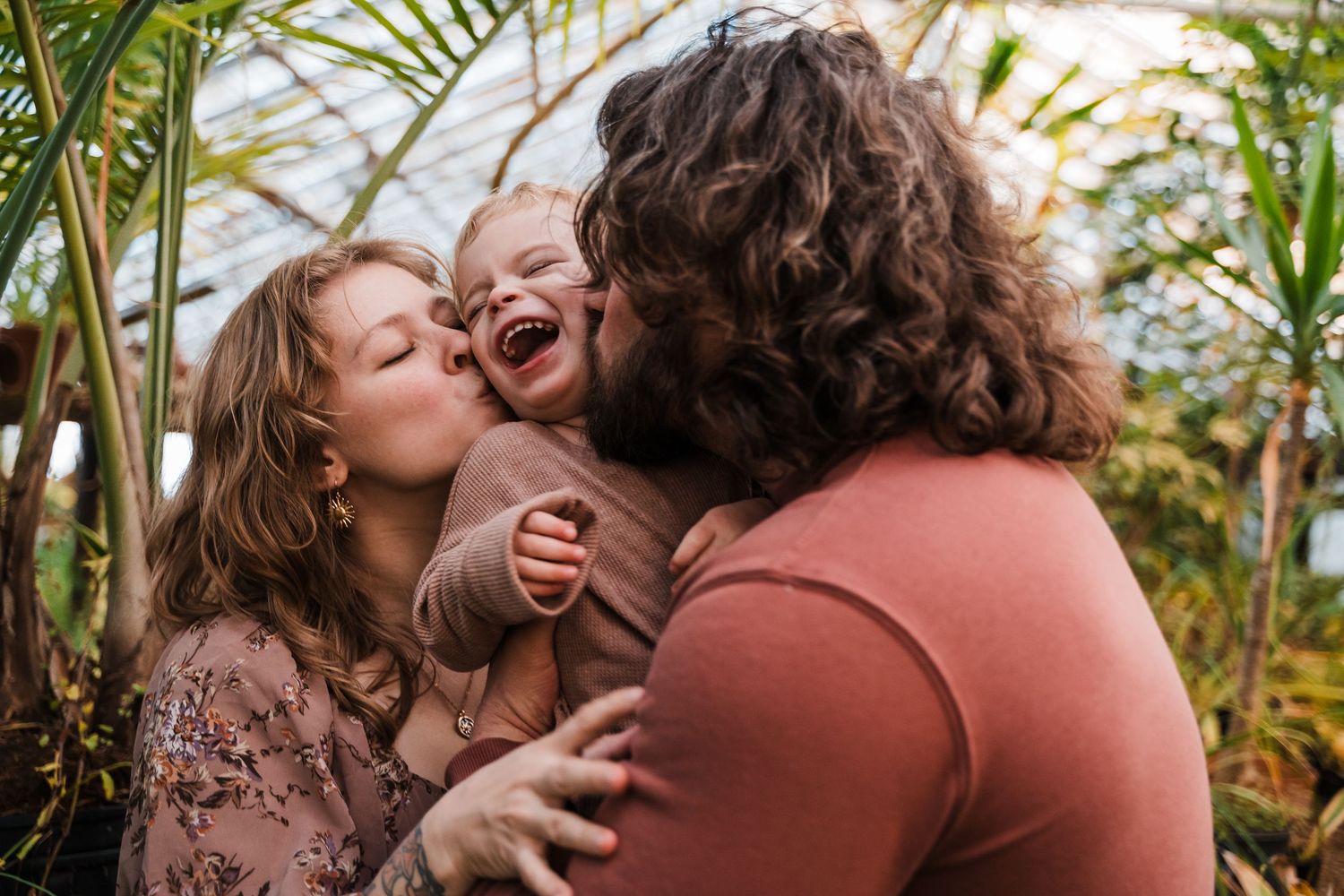 Intimate family moment surrounded by tropical greenhouse plants.