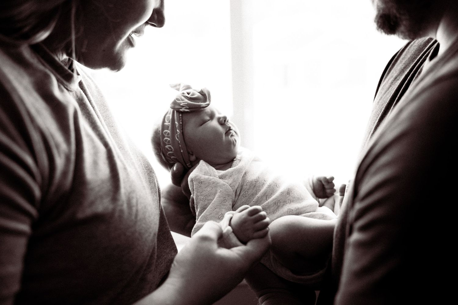 A tender black and white photograph captures an intimate family moment between parents and a small child.